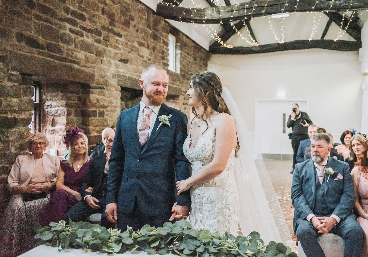A wedding ceremony in progress inside a rustic venue with stone walls.