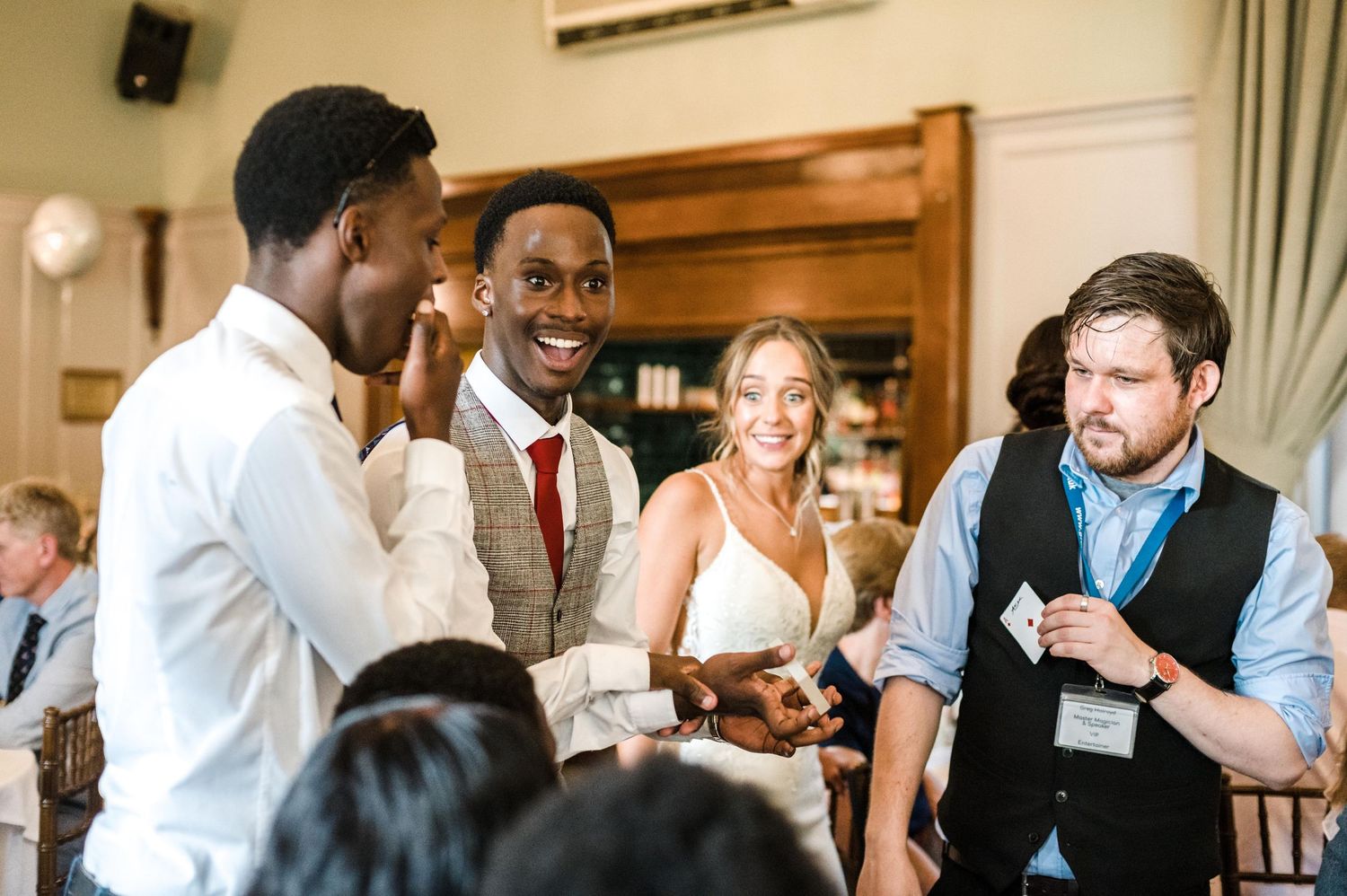 Wedding reception guests engaged in animated conversation at indoor venue.