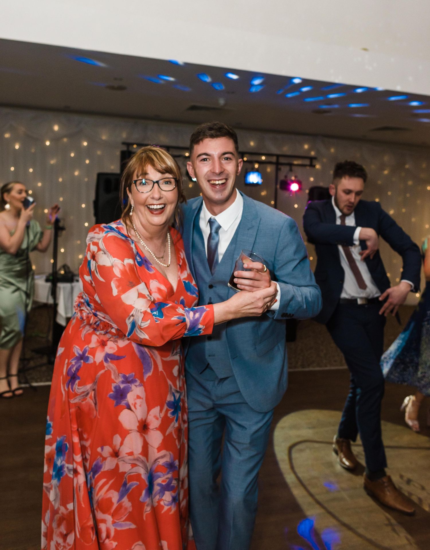 A celebratory dance moment at a wedding reception with colorful lighting and festive atmosphere.