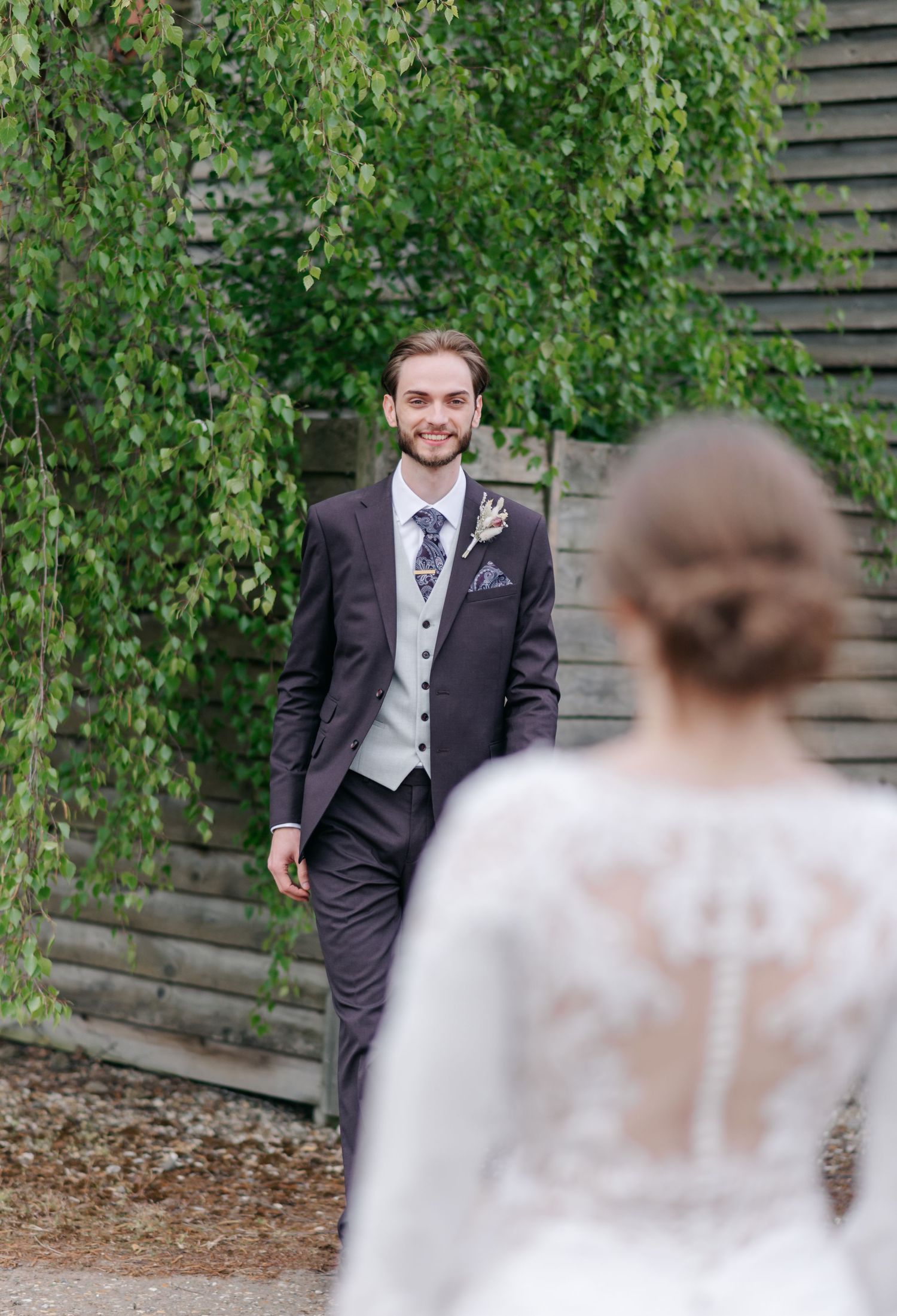 First look wedding moment captured in garden setting with green foliage.