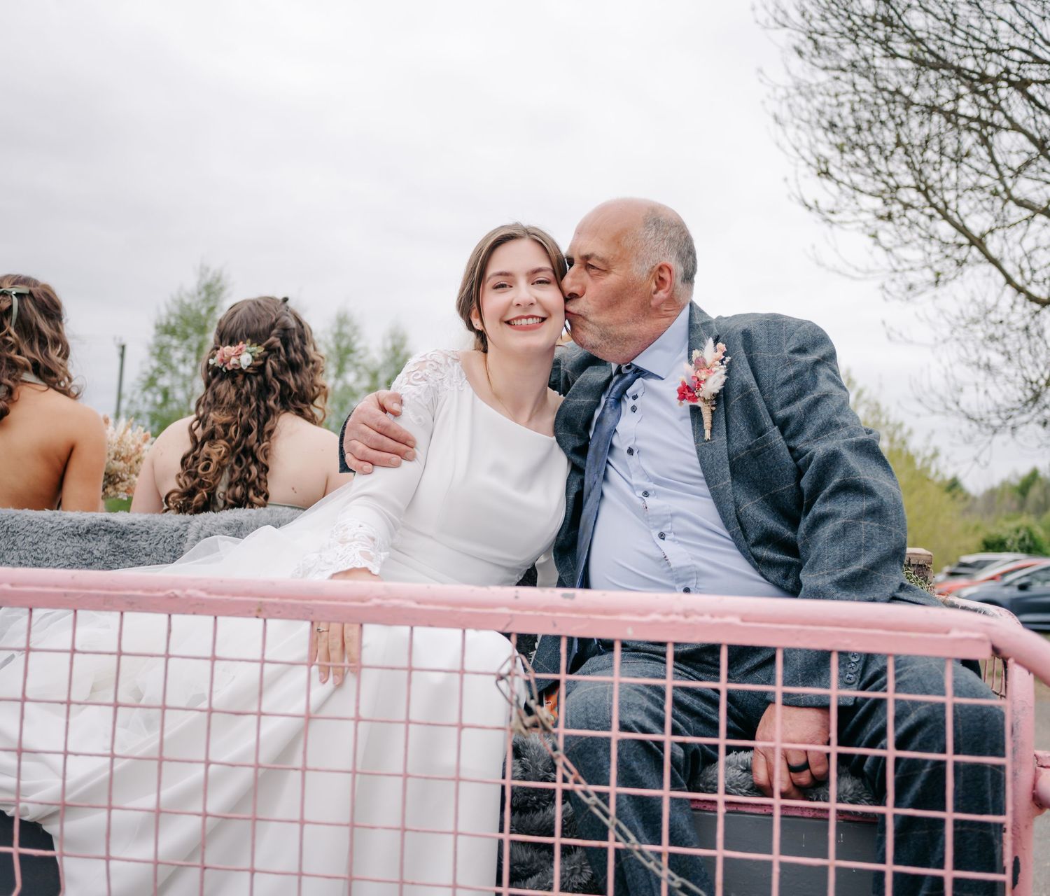 Romantic wedding couple posing on a pink vintage truck in a countryside setting.