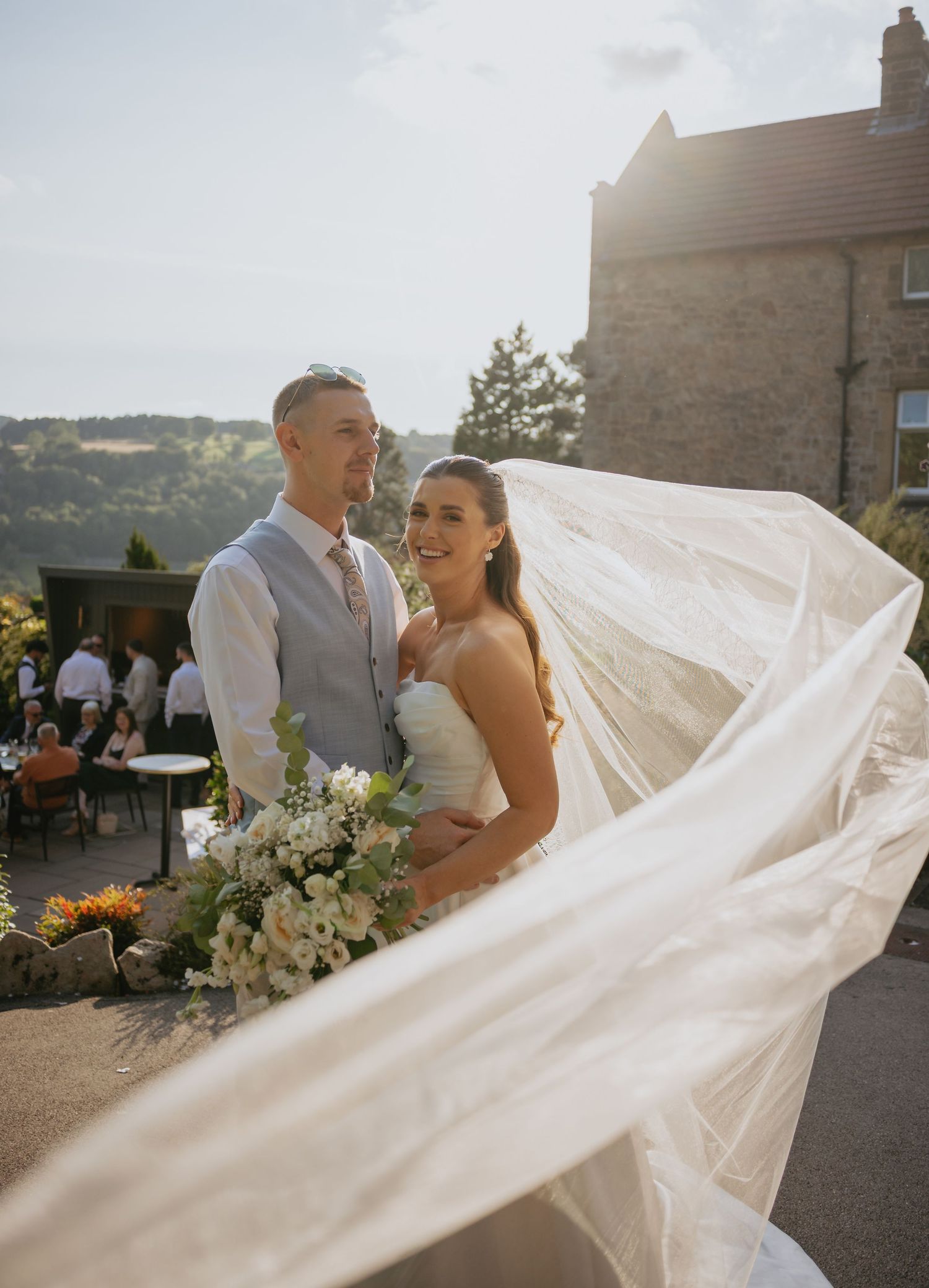 Flowing wedding veil catches the sunlight during outdoor wedding portraits.