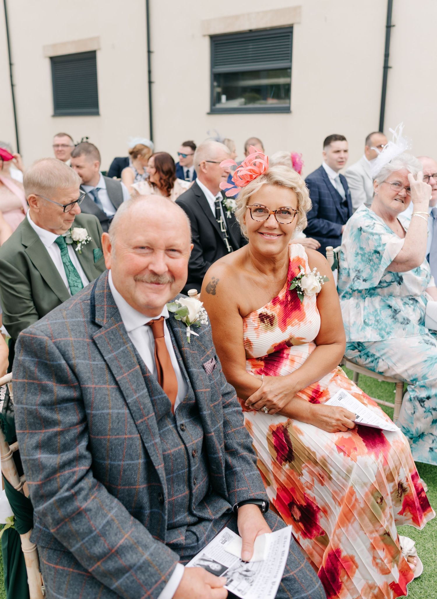 Wedding guests share joyful laughter during an outdoor ceremony celebration.