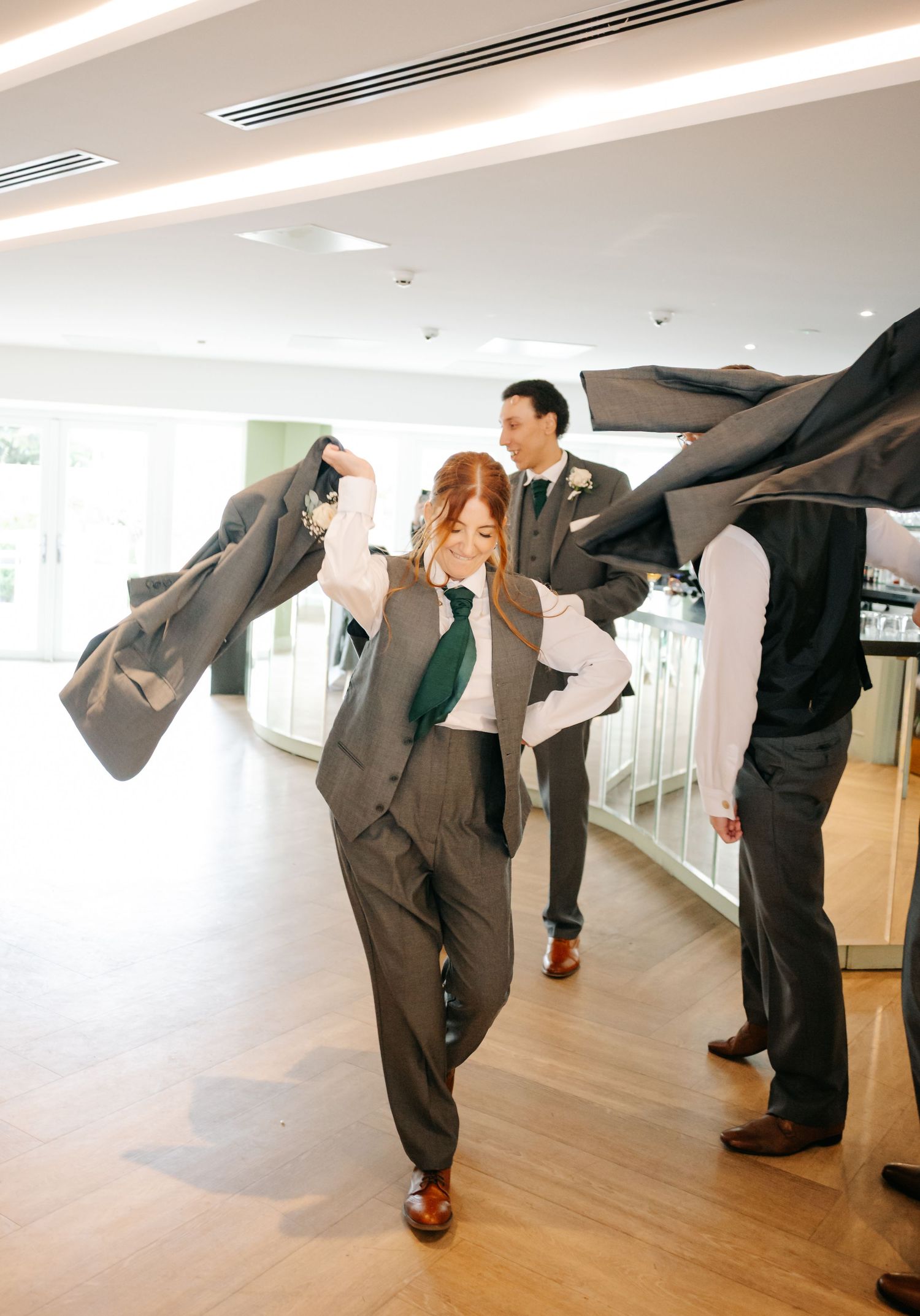 Groomsmen performing synchronized dance moves in grey suits.
