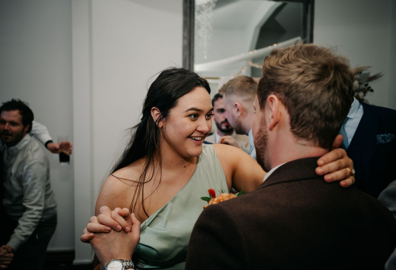 Candid moments of wedding guests laughing and embracing during reception celebrations.