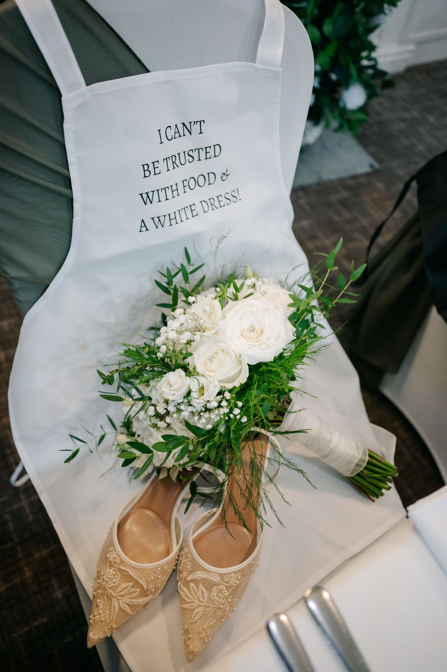 Elegant bridal shoes and white floral bouquet arranged with delicate greenery and roses.