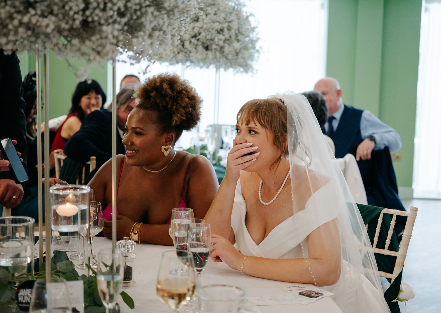 Wedding guests seated at reception tables sharing joyful conversations.
