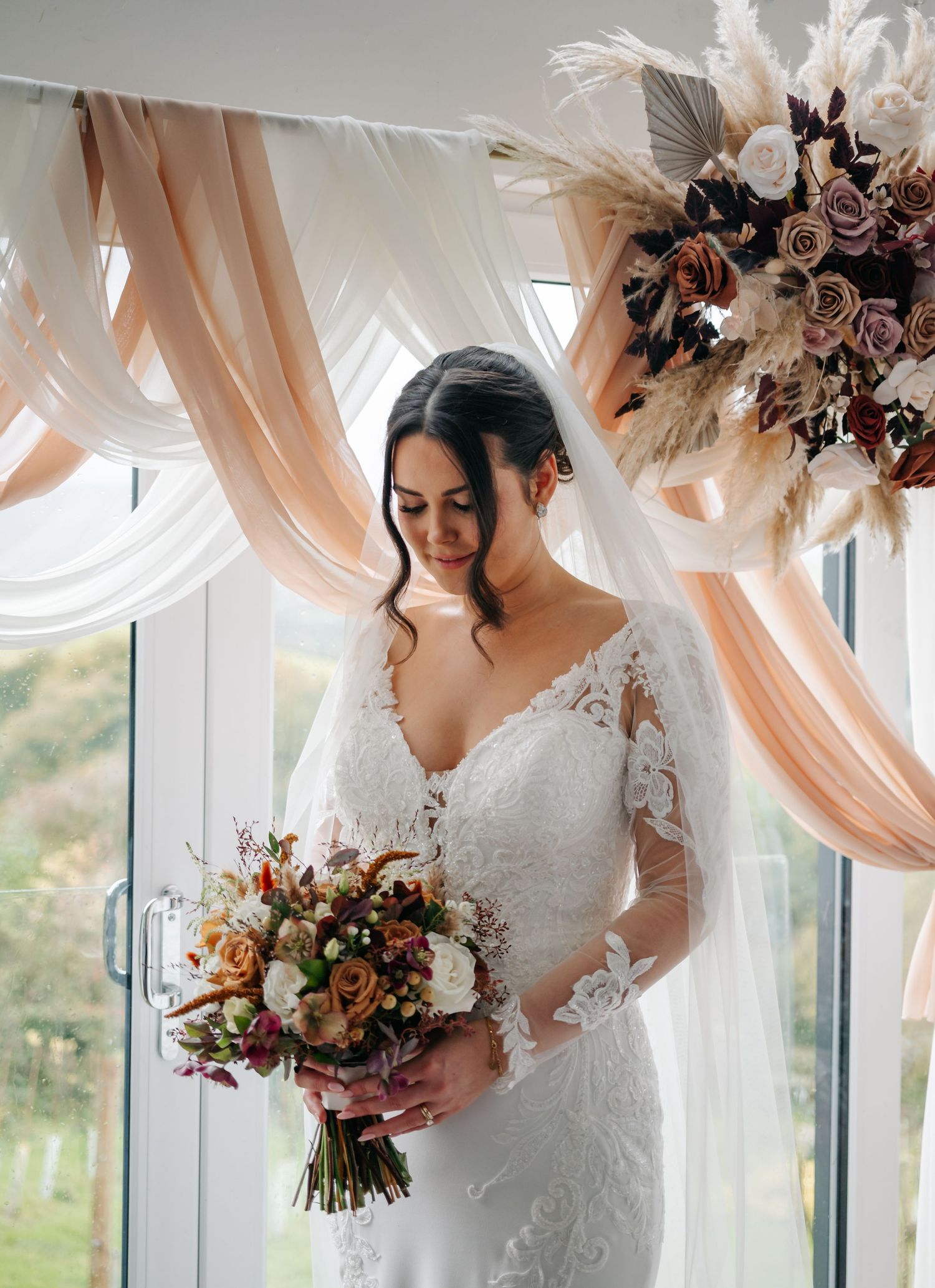 Wedding bouquets featuring white and peach flowers against a backdrop of flowing curtains and natural light.