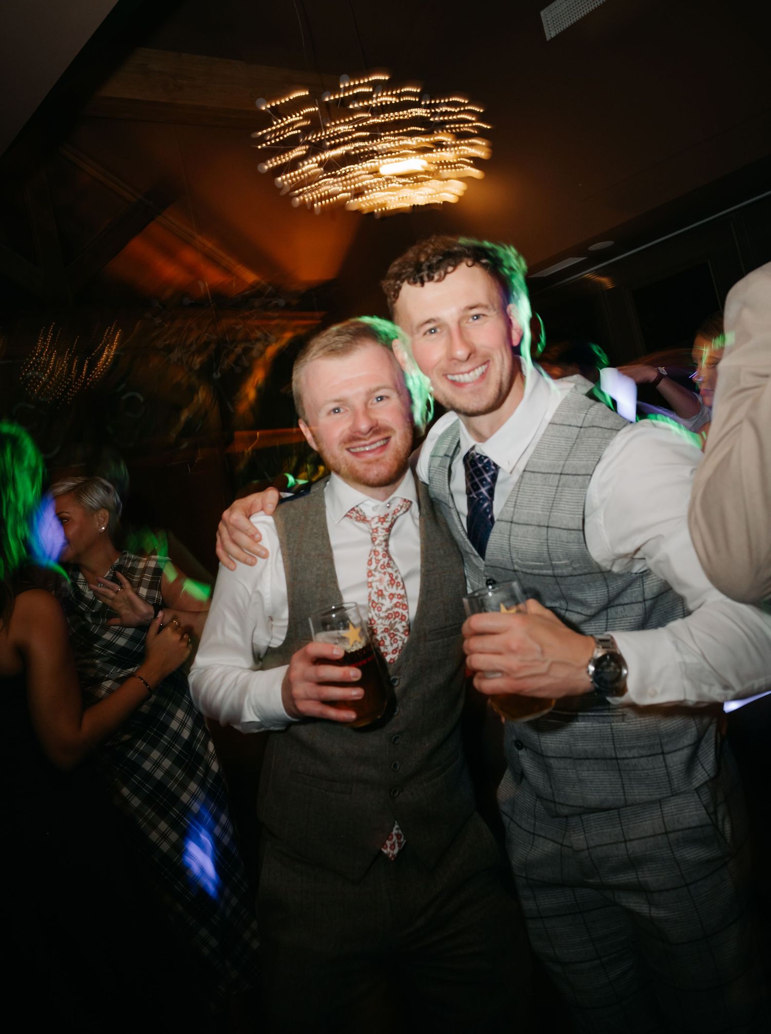 Wedding reception party scene with colorful lighting and guests celebrating on the dance floor.