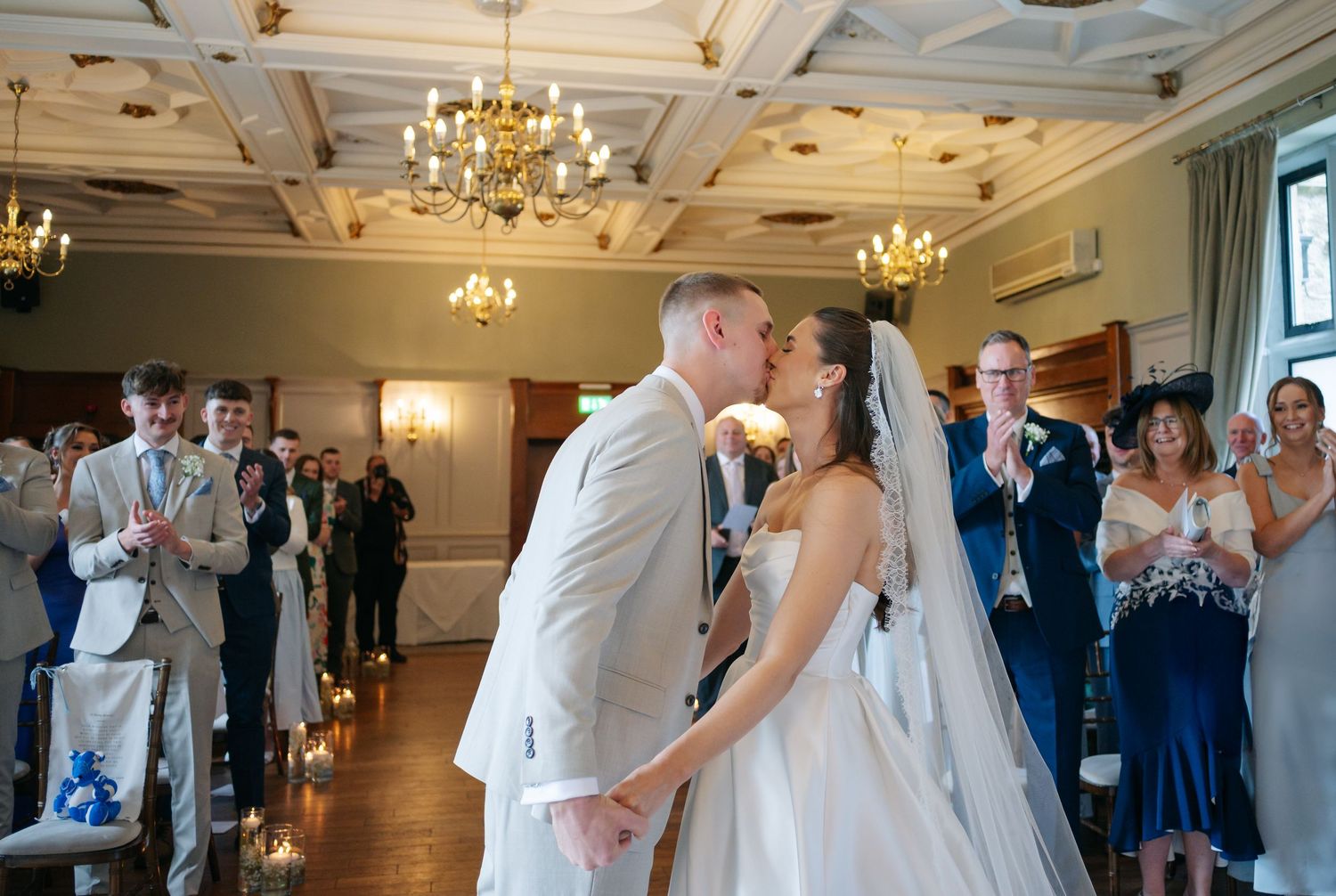 Elegant wedding reception hall with chandeliers features couples dancing in formal attire on a polished wooden floor.
