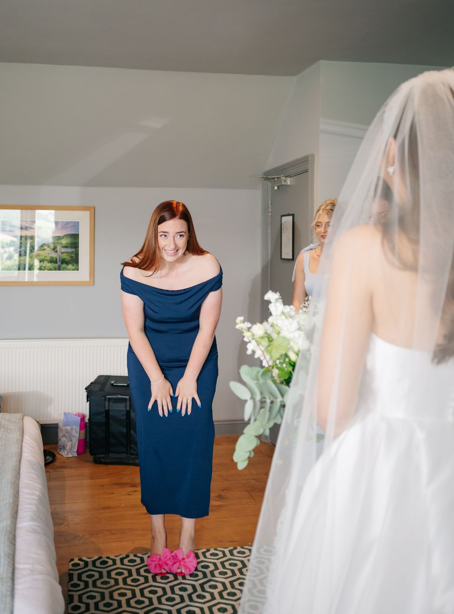 A wedding party member in a navy dress and pink shoes stands in preparation for the ceremony.