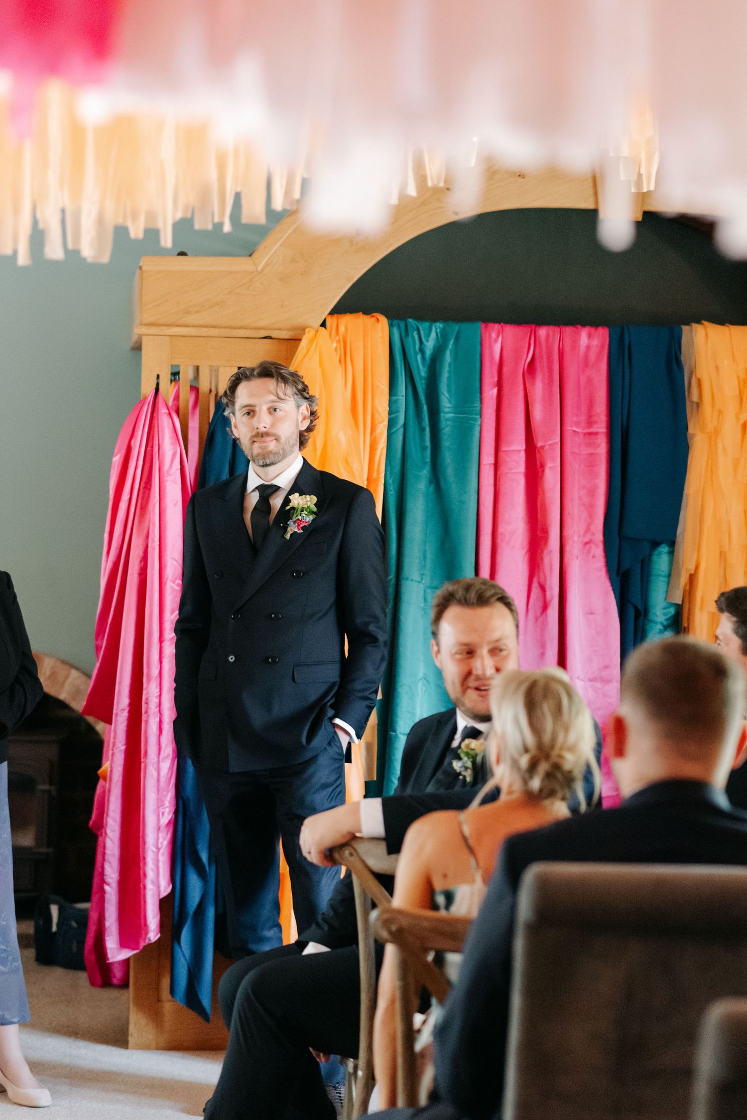 Wedding ceremony setup with colorful fabric backdrop panels in pink, yellow and teal.