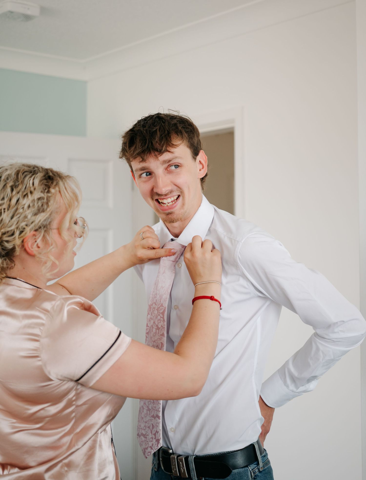 Wedding preparations show adjusting of formal attire in a bright indoor setting.