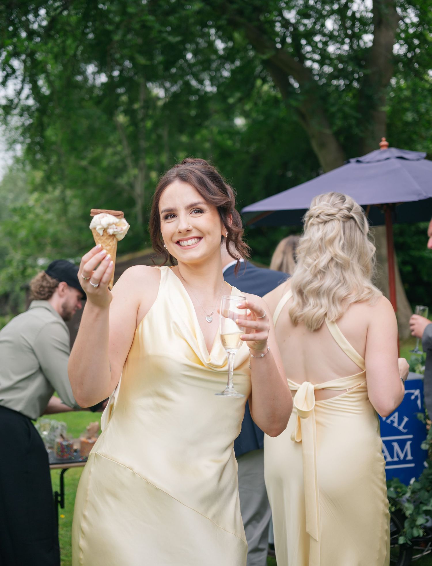 Bridesmaids in pale yellow dresses celebrating at outdoor wedding reception.