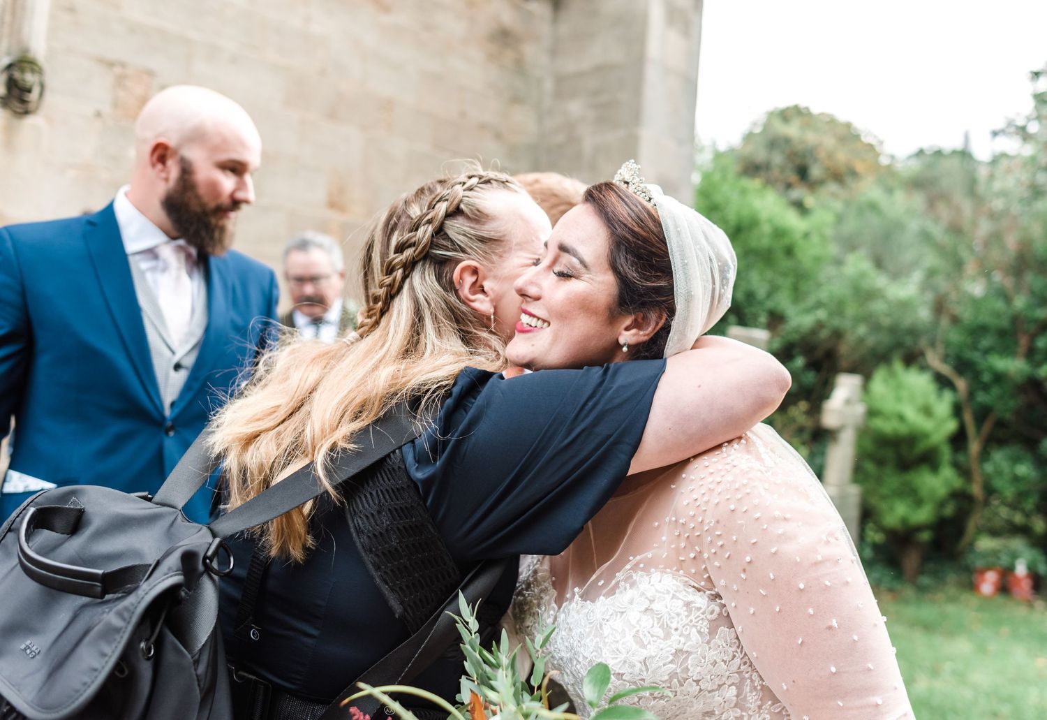 Emotional wedding guests share warm embraces during outdoor celebration.
