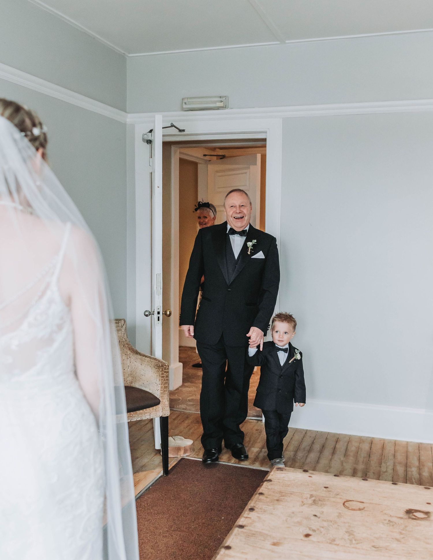 A heartwarming wedding day first look in a white room with wooden floors.