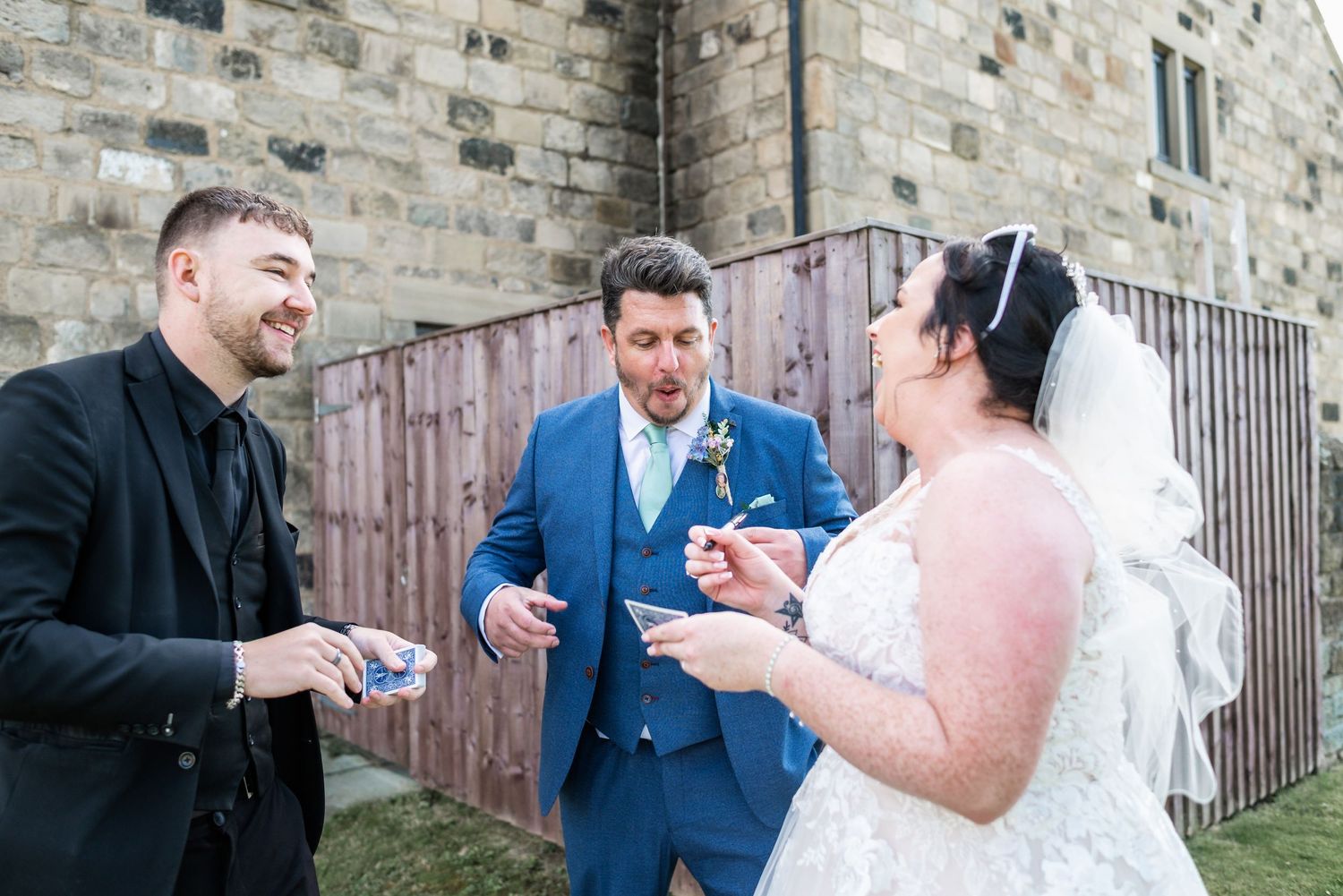 Casual outdoor moment between wedding party members against stone wall backdrop.