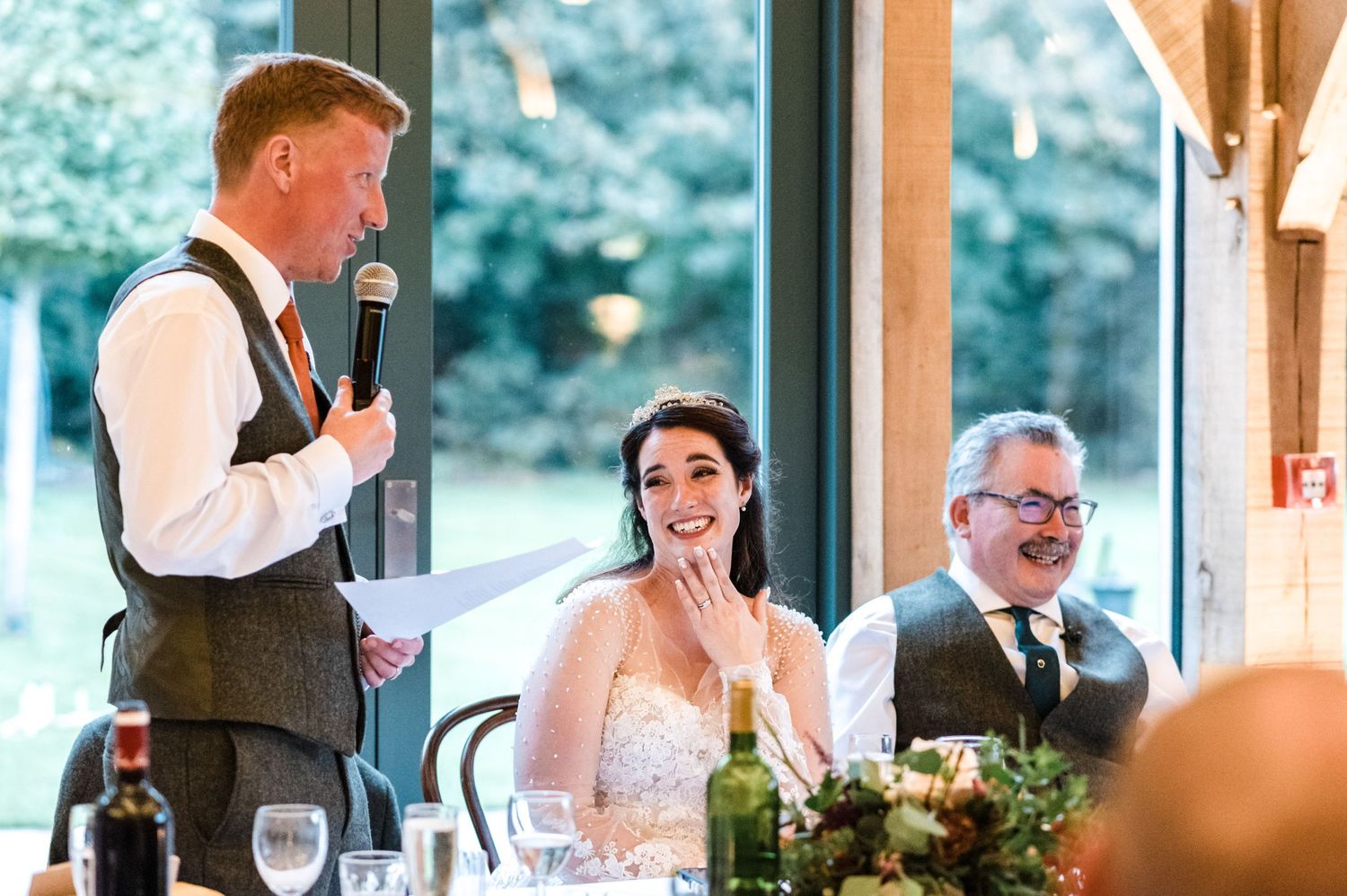 Best man gives an emotional wedding speech while bride and guests react during reception.