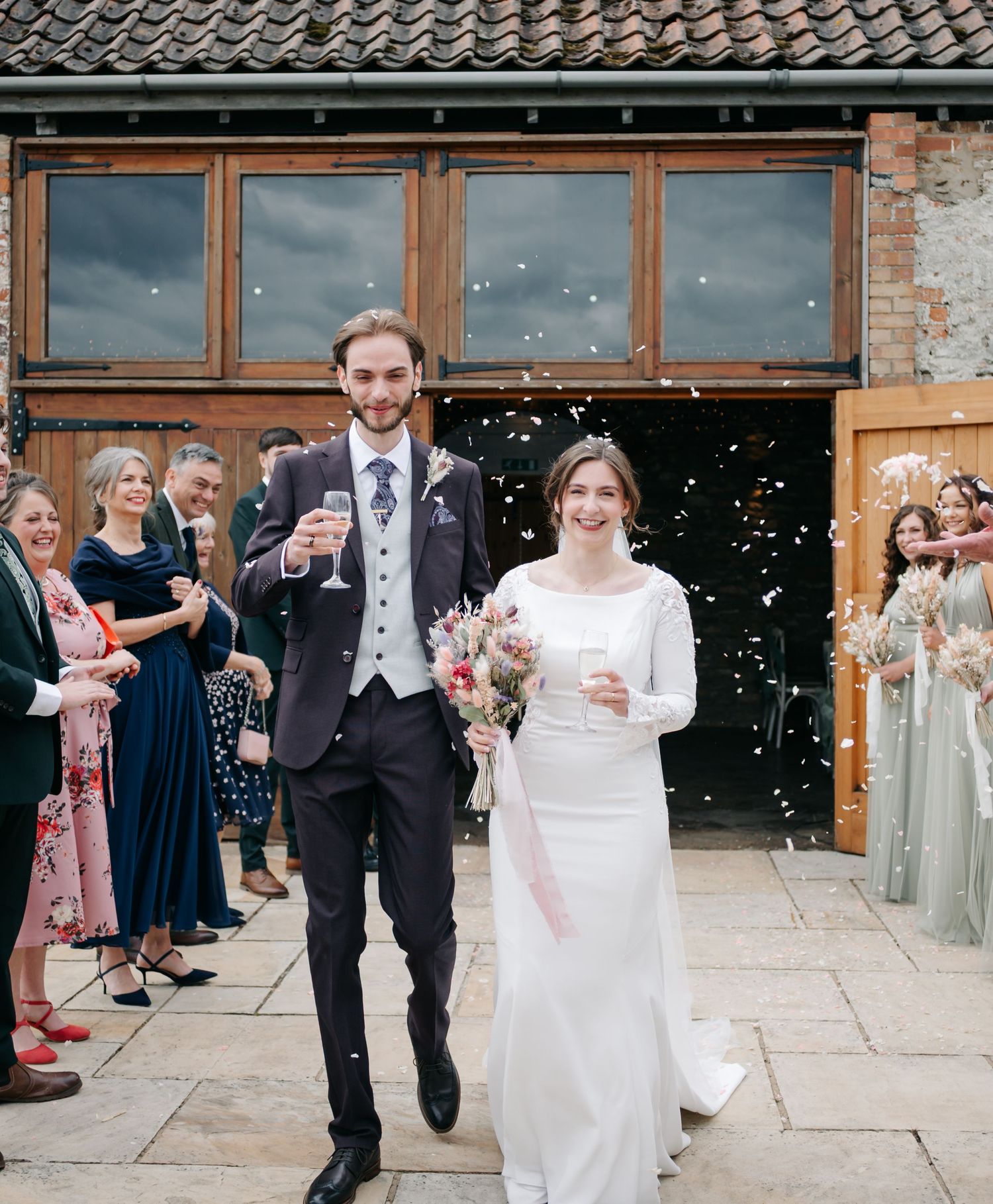 Wedding guests throw confetti outside a venue as the newlyweds celebrate their special day.