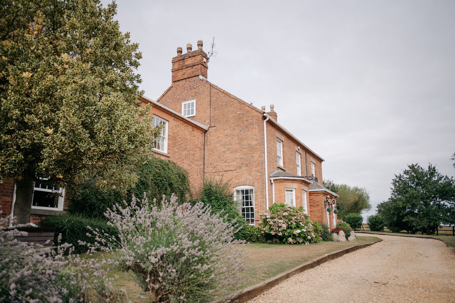 Collection of exterior views of a traditional English brick farmhouse and its surrounding scenic grounds and gardens.