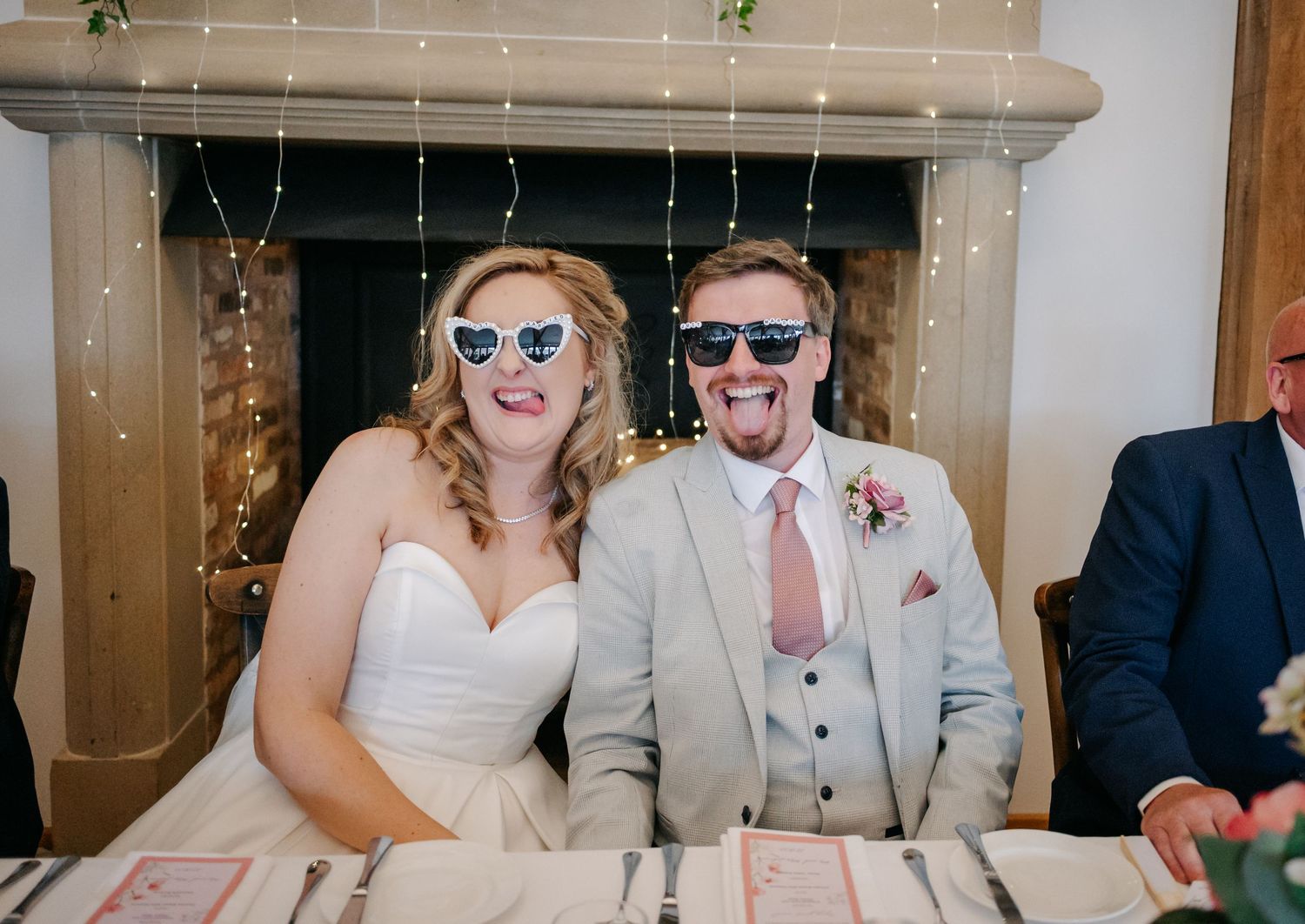 A couple wearing sunglasses share a fun moment at their wedding reception.