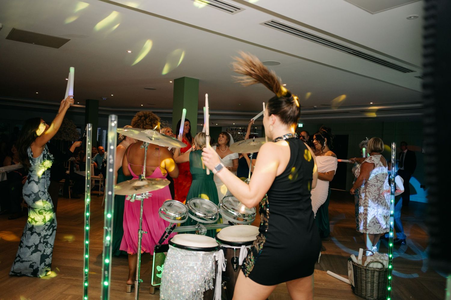 Wedding party guests dancing and celebrating on a dimly lit dance floor.