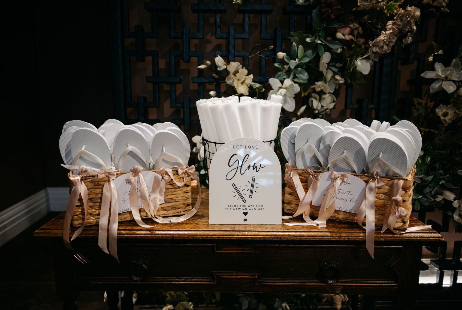 White wedding favors and decorative items arranged on a wooden display table.