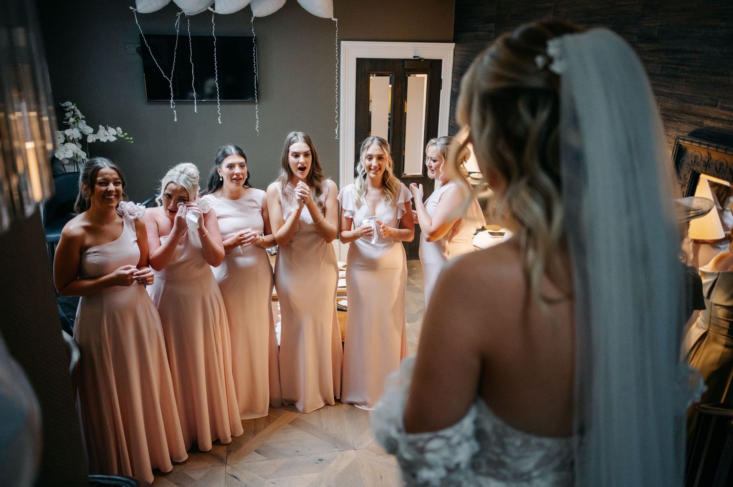 Row of bridesmaids in blush pink dresses standing together at a wedding.