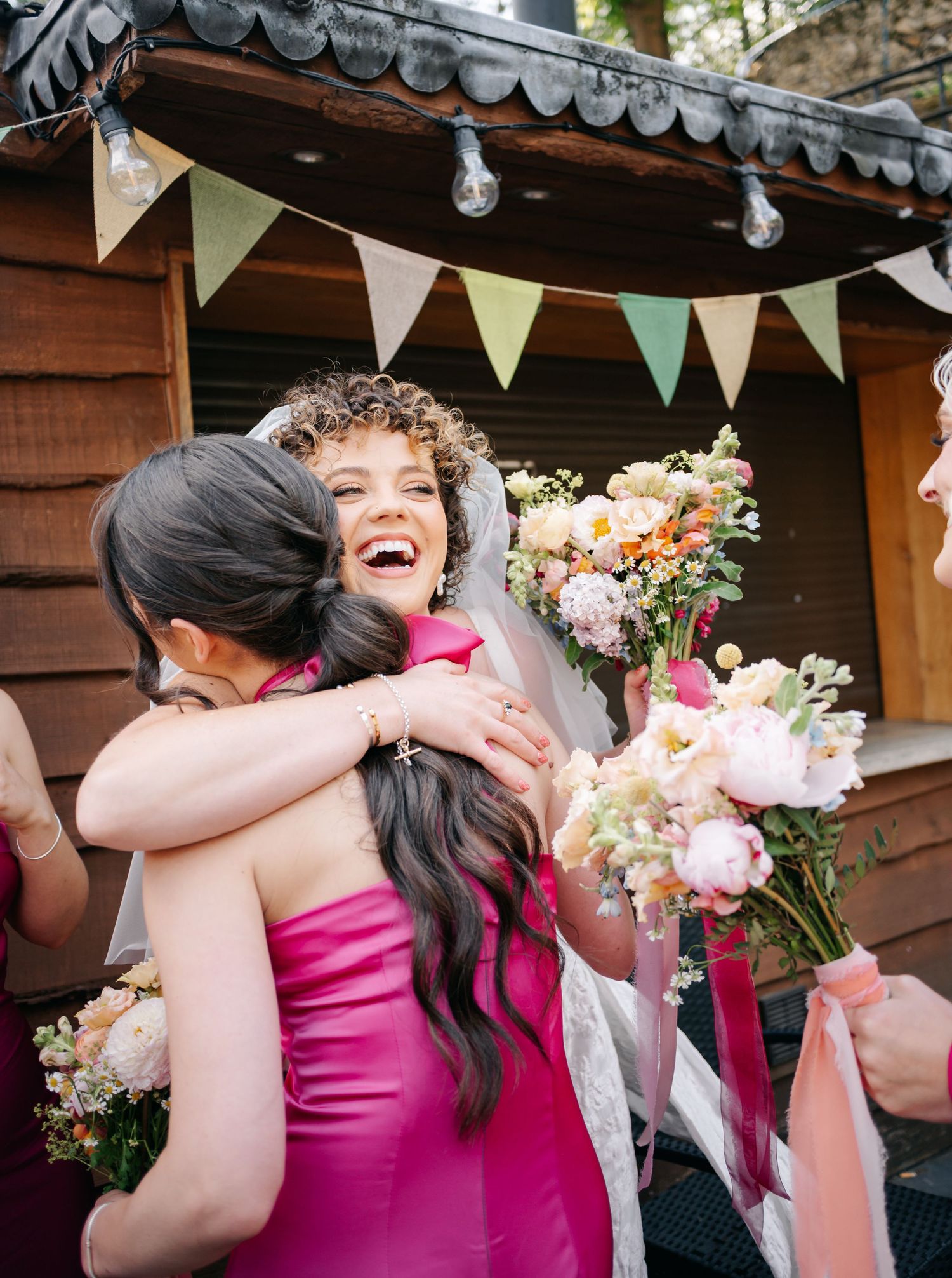 Joyful wedding celebration moment with pink bridesmaid dress and floral decorations.