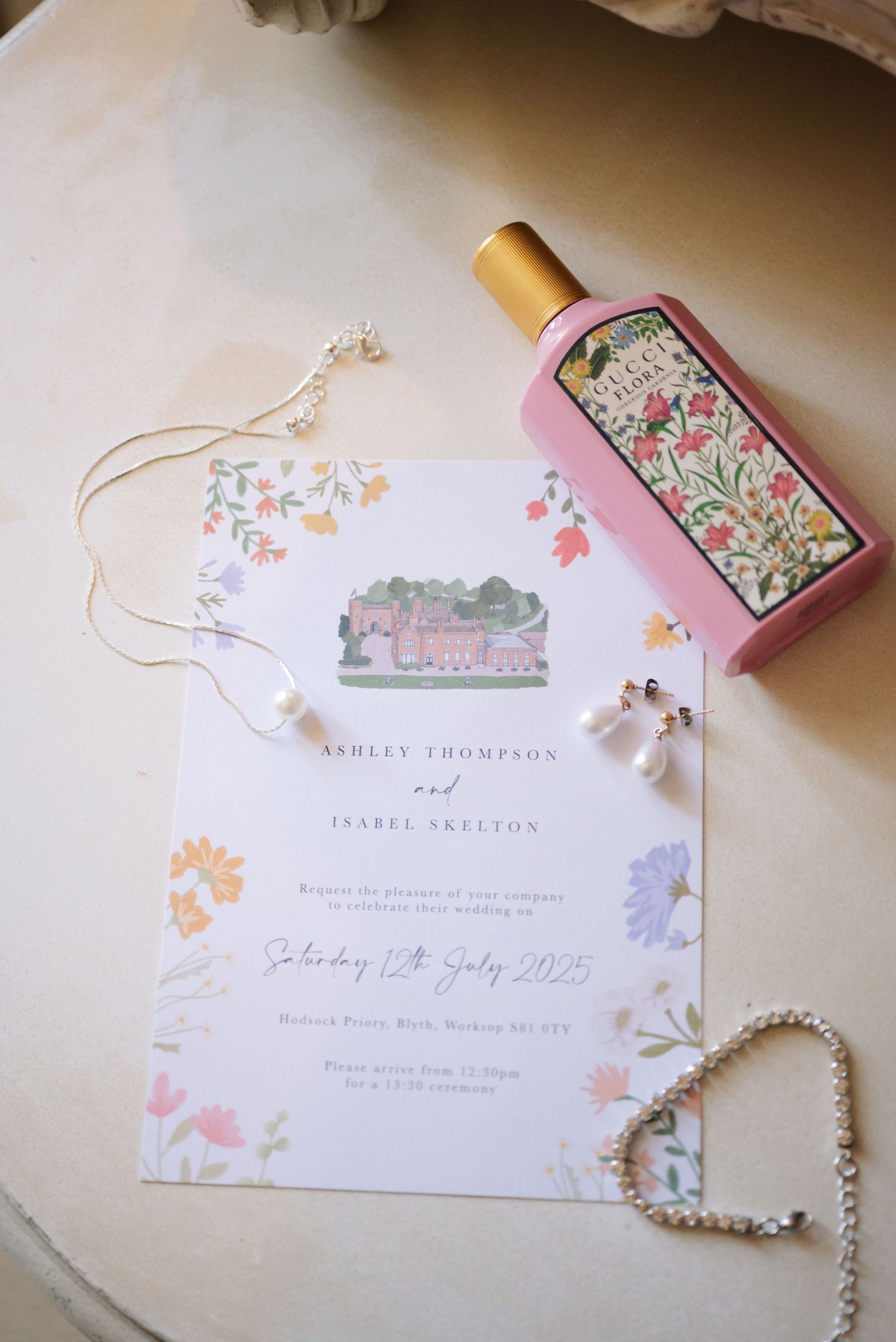 Delicate wedding invitations with floral designs and handwritten details laid out on a light surface.