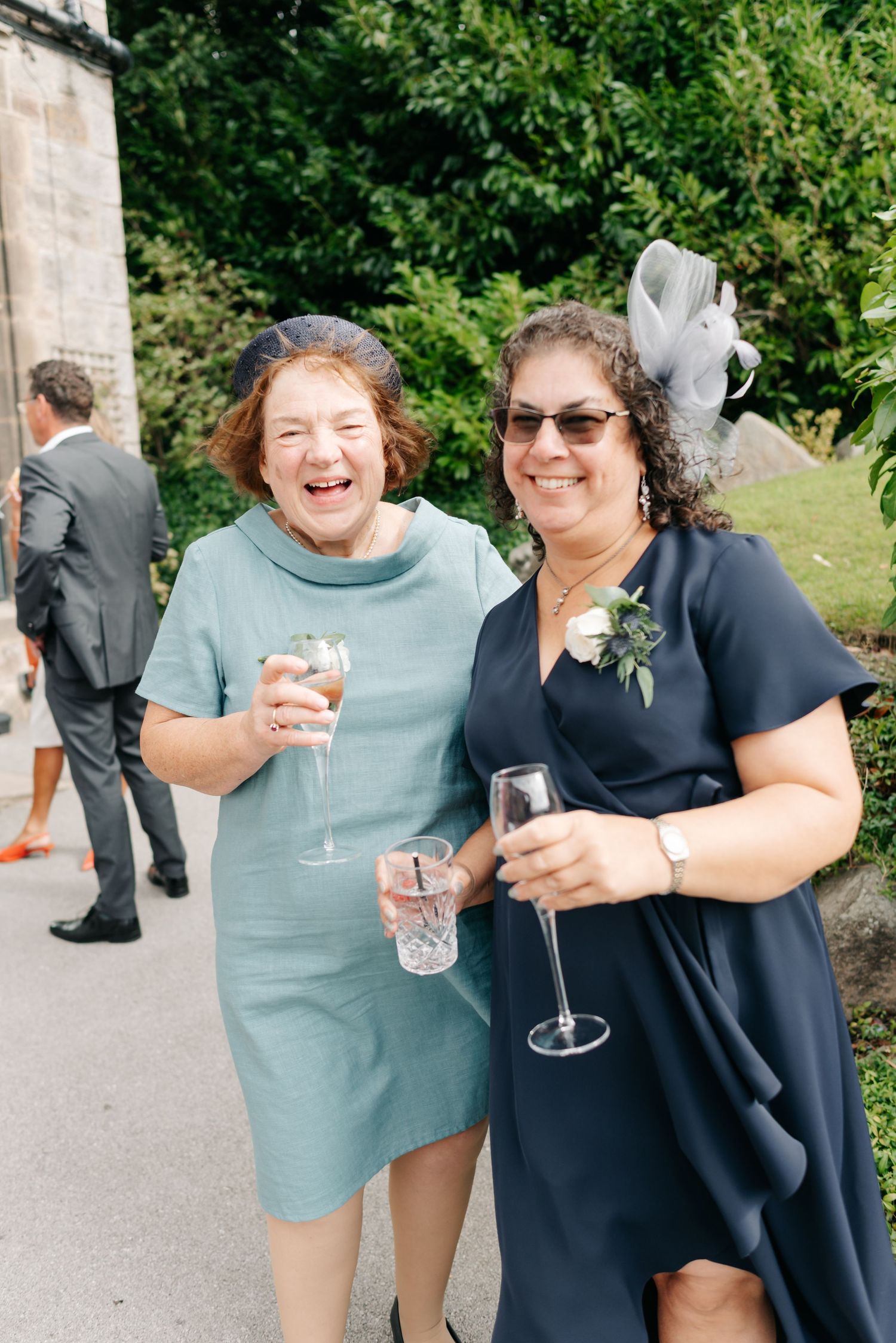Wedding guests enjoying drinks and laughter during outdoor reception.