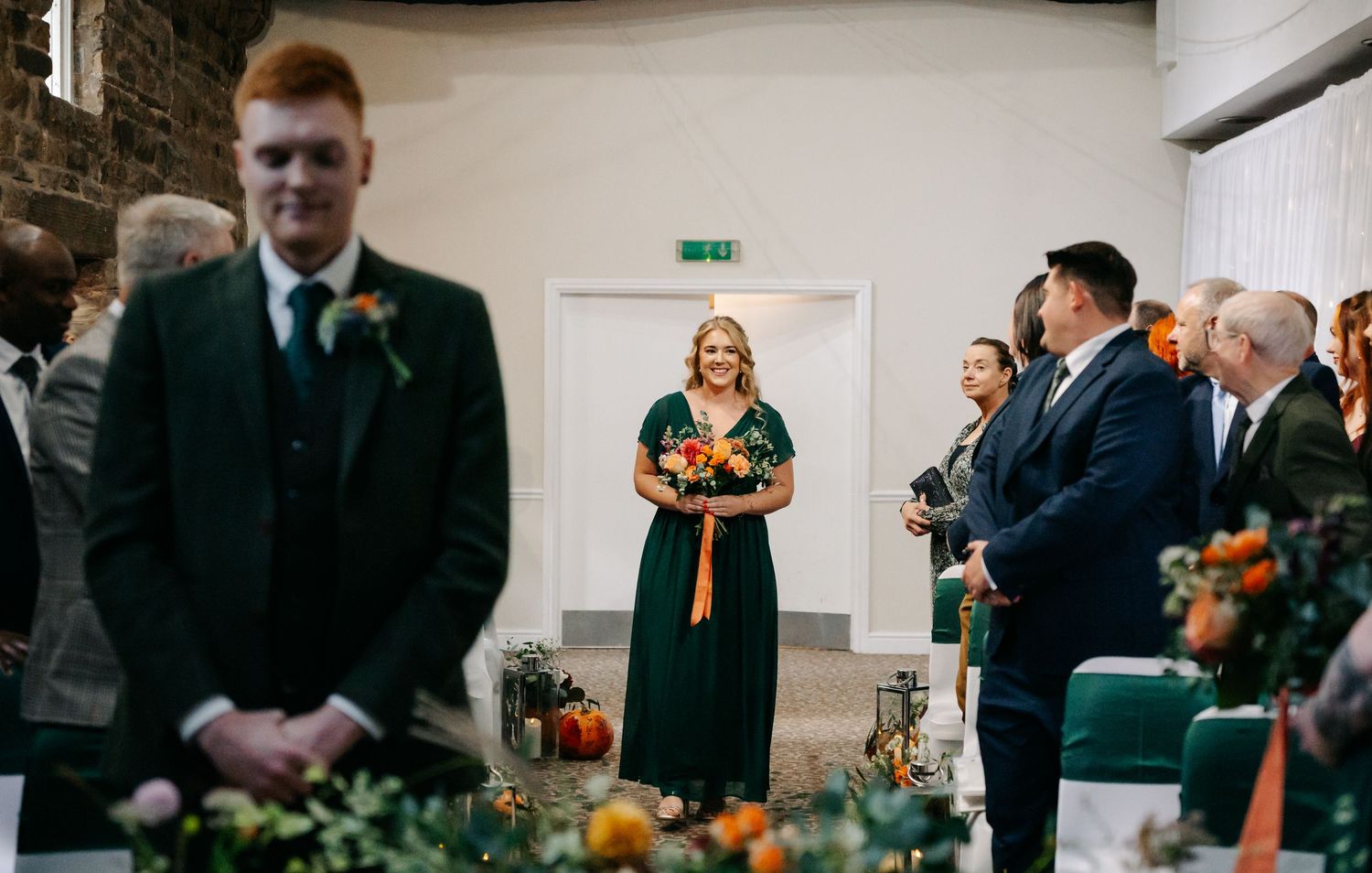 Wedding ceremony in progress inside a rustic stone venue with autumn decorations.