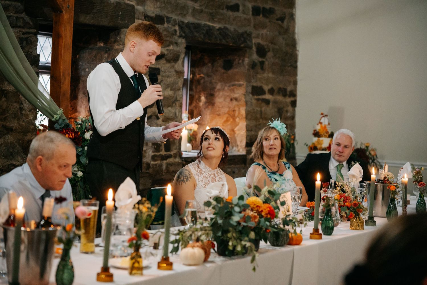 Wedding reception dinner setup in rustic brick venue with long tables and candlelight.