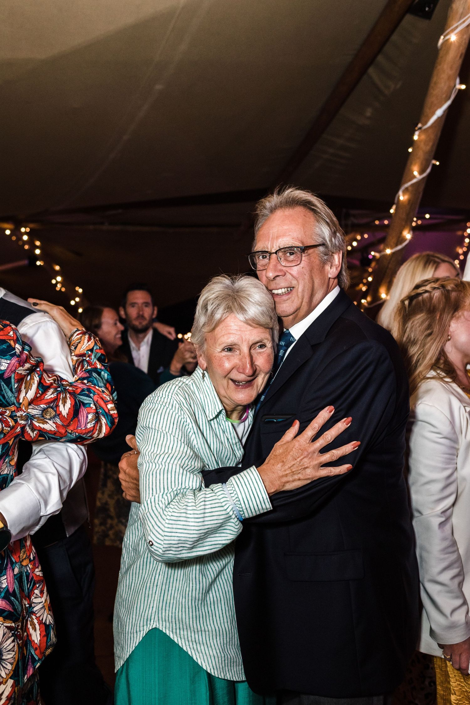 Guests embracing during a joyful moment at a wedding reception.