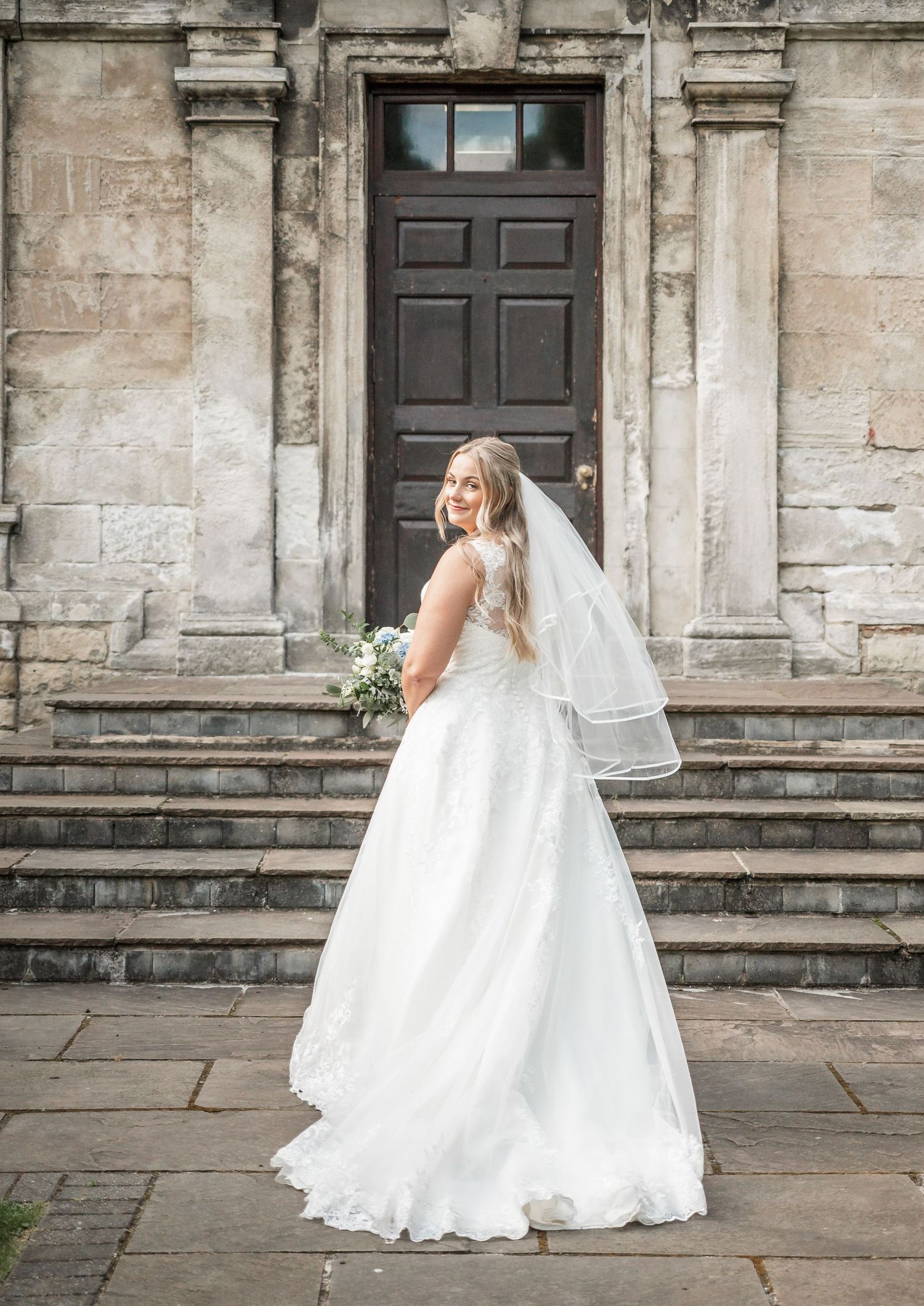 Elegant white wedding gown photographed against historic stone architecture.