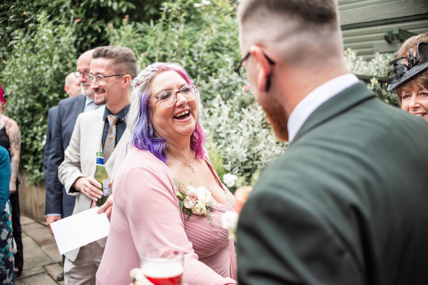 Wedding guests share laughter during outdoor celebration.