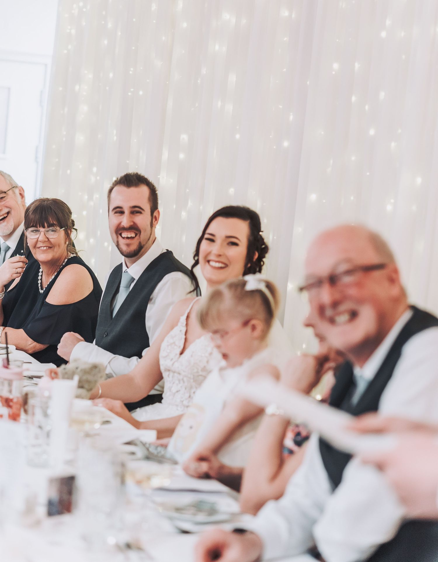 Wedding reception dinner with guests laughing and enjoying the celebration at a decorated table.