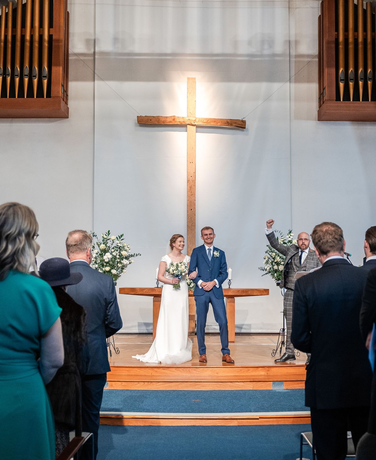 Traditional church wedding ceremony with wooden altar, illuminated cross, and floral arrangements.