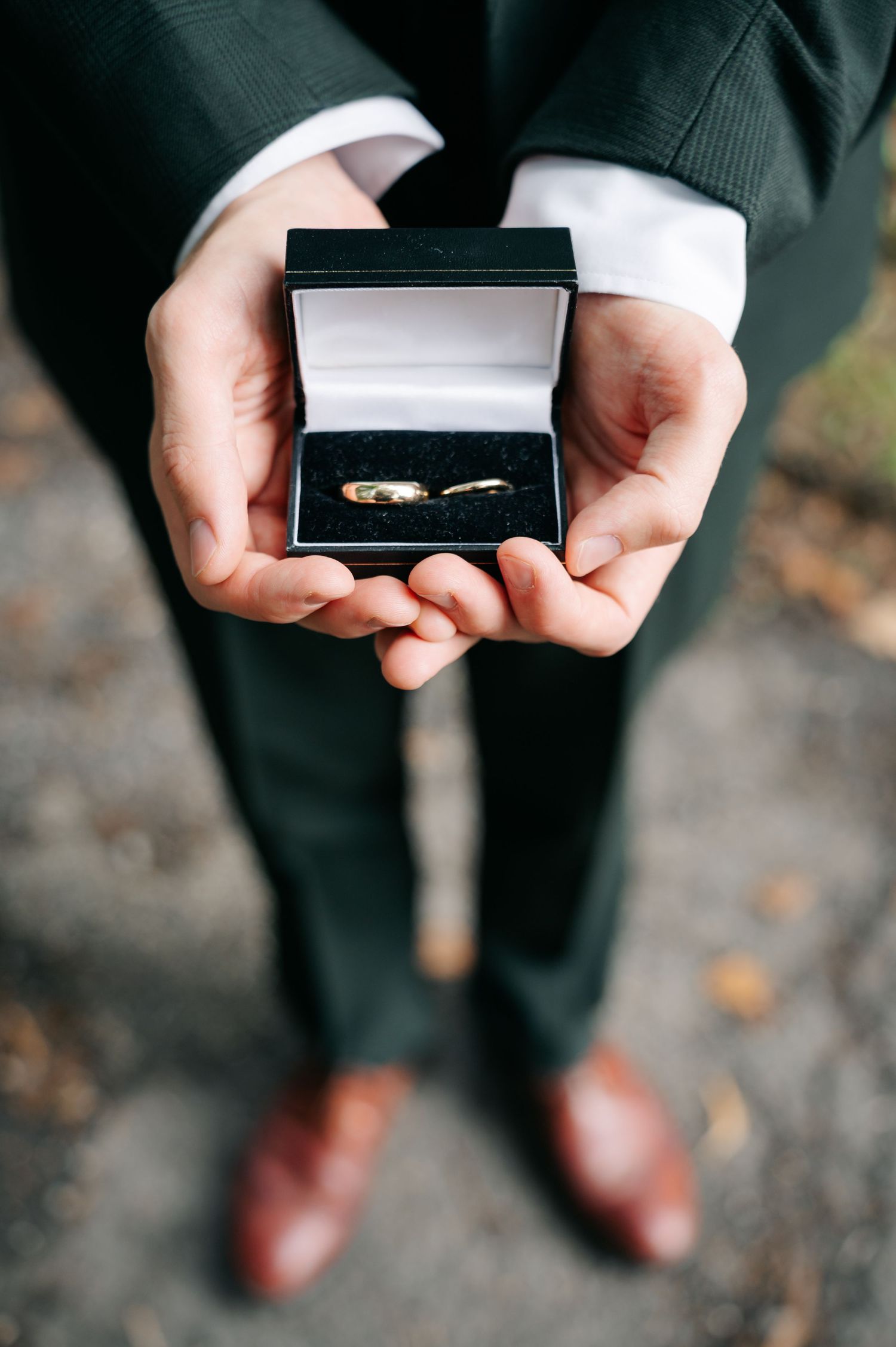 Close-up sequence showing hands holding a small black ring box being opened.