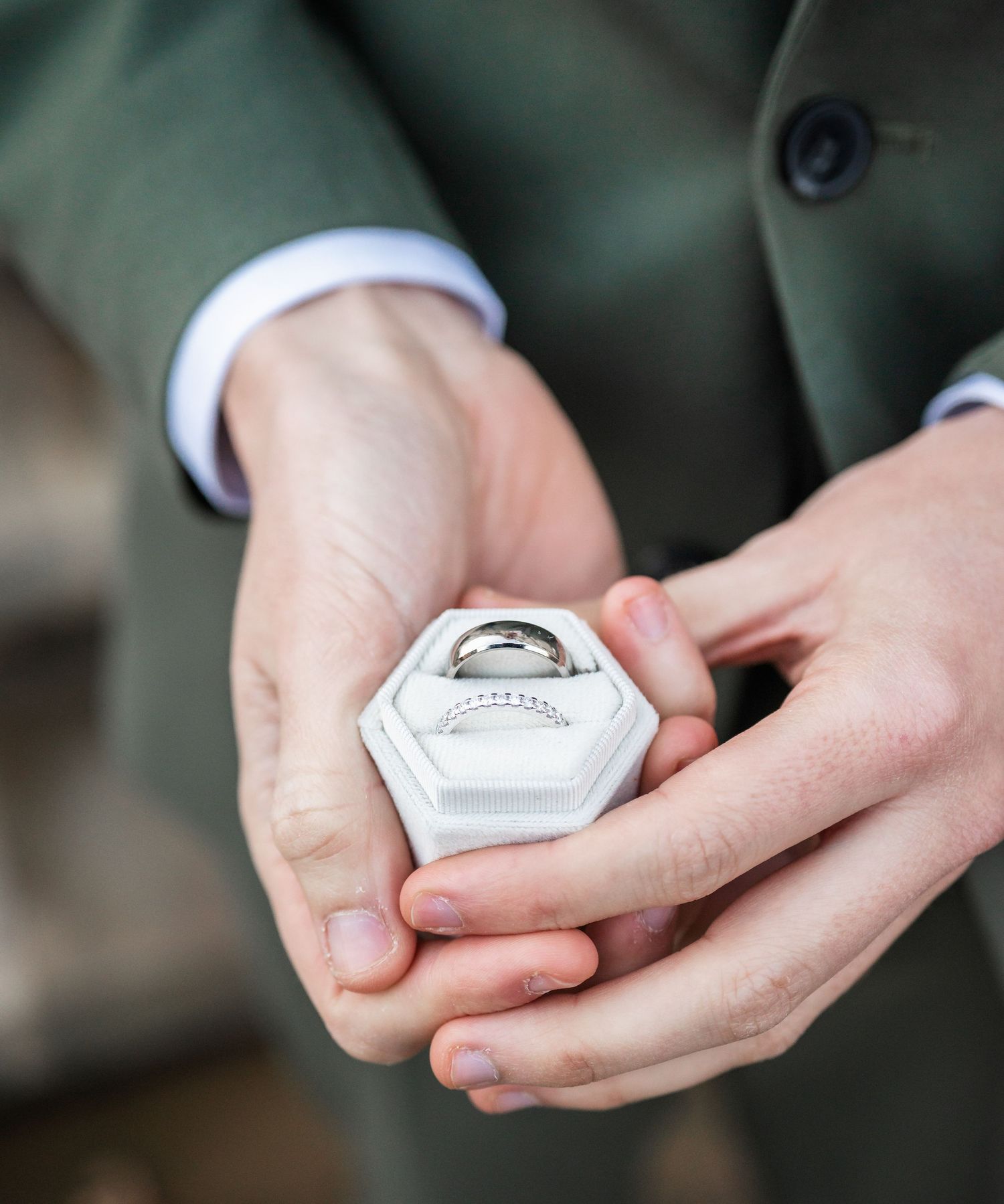 Close-up of hands holding a hexagonal white ring box.
