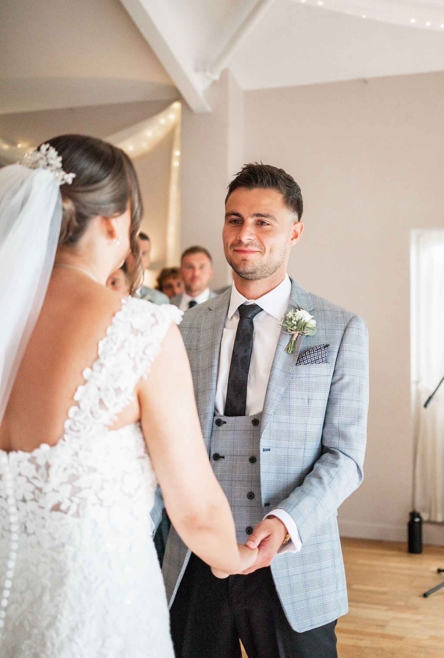 An intimate wedding ceremony moment with the couple exchanging vows in a light-filled room.