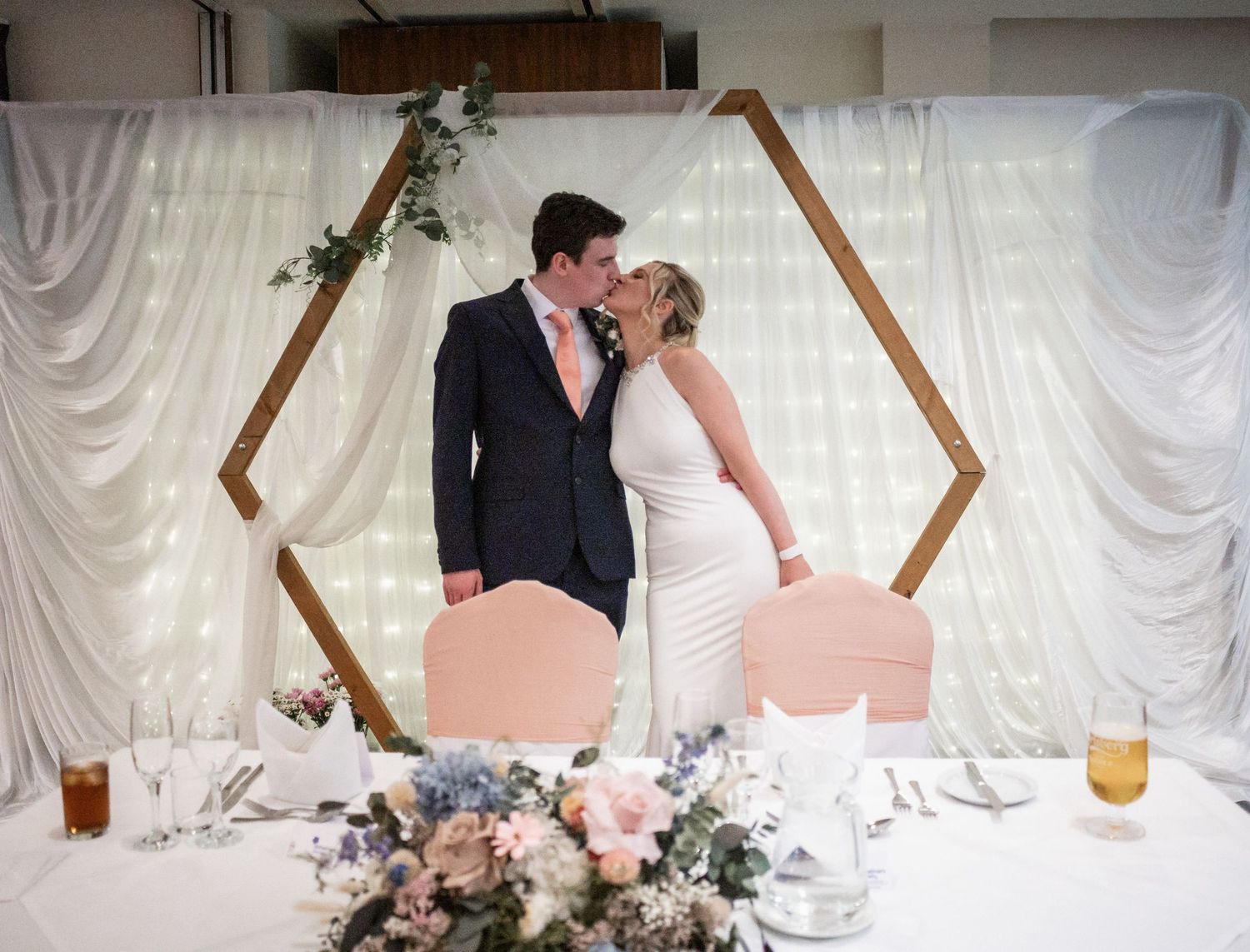 A couple shares a moment together in a reception venue with elegant table settings and decor.