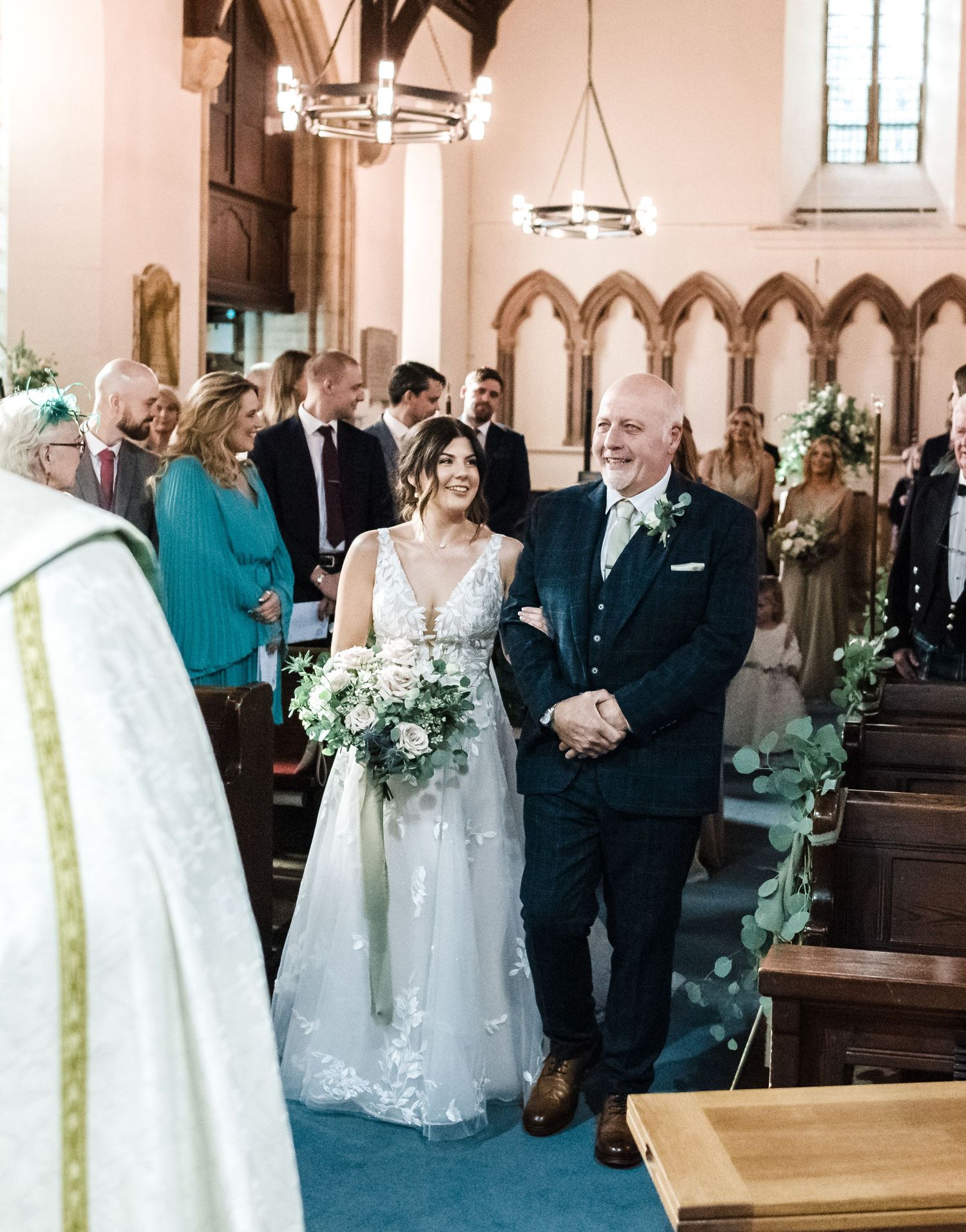 Traditional church wedding ceremony with floral aisle decorations and arched windows.
