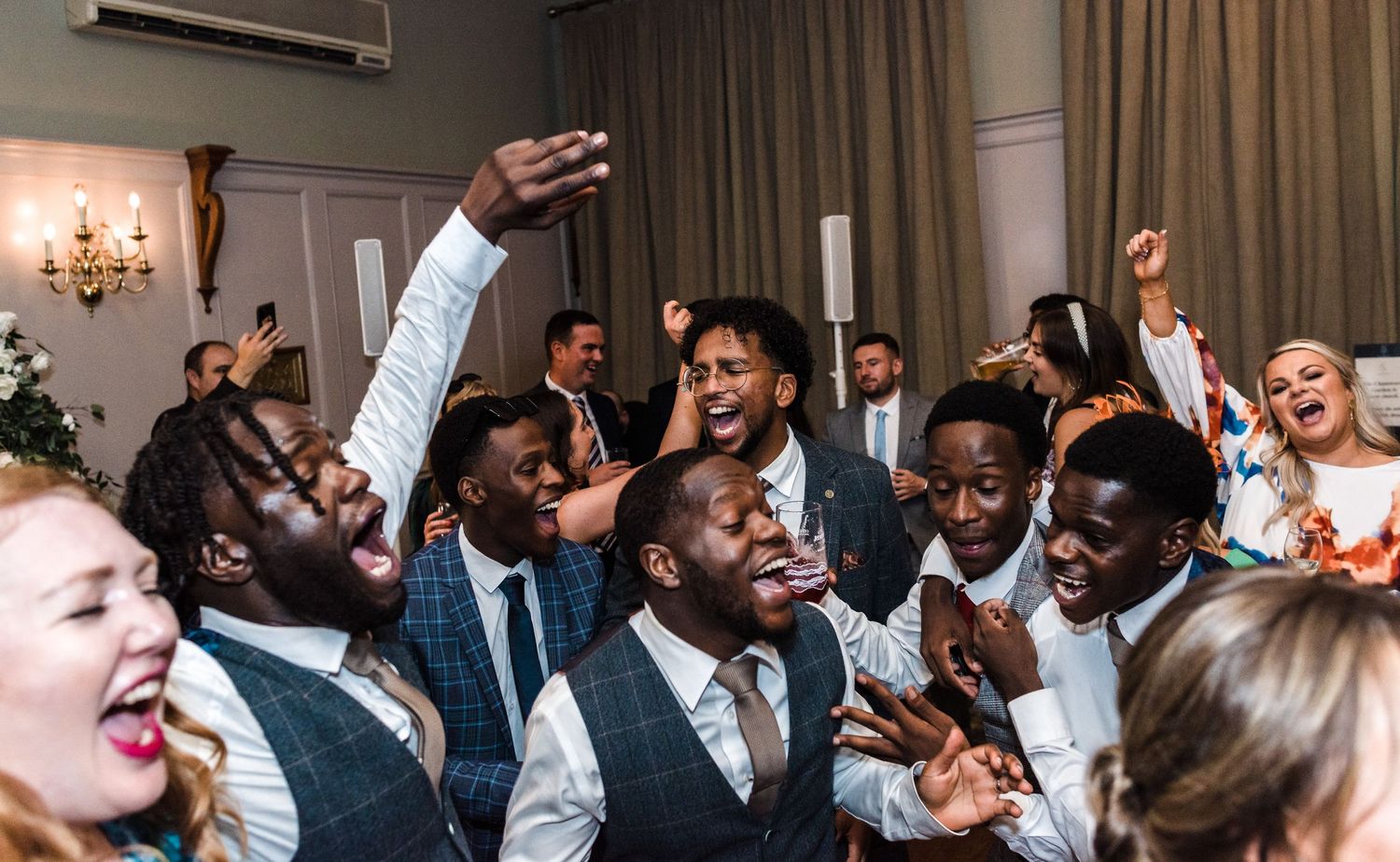Energetic wedding guests dancing and celebrating at indoor reception.