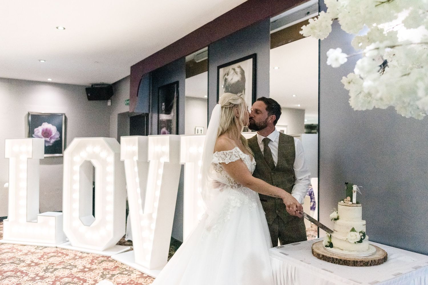 Newlyweds share an intimate moment in front of large LOVE letters at their wedding reception.