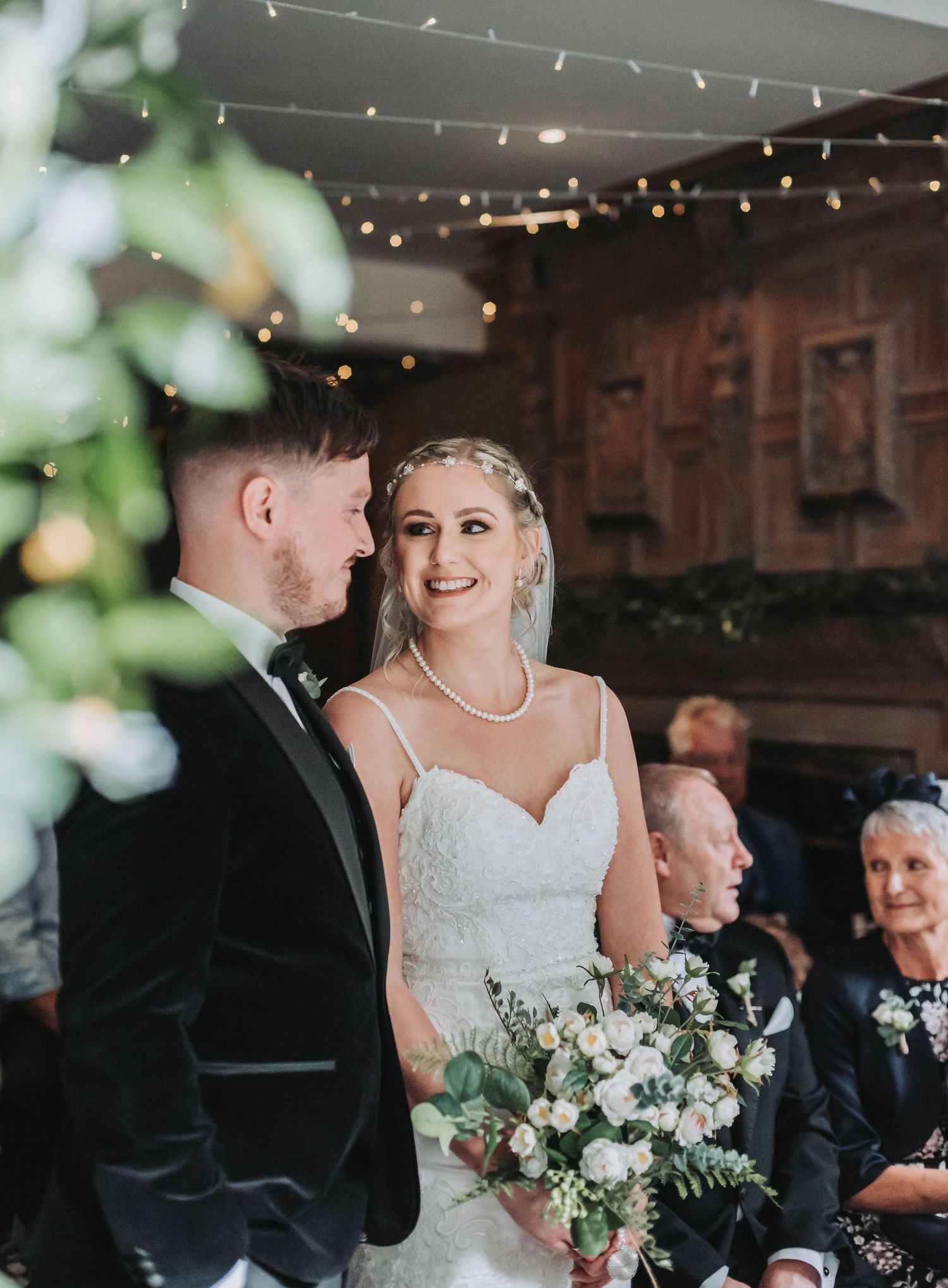 A couple exchanges loving glances during their wedding ceremony under string lights.