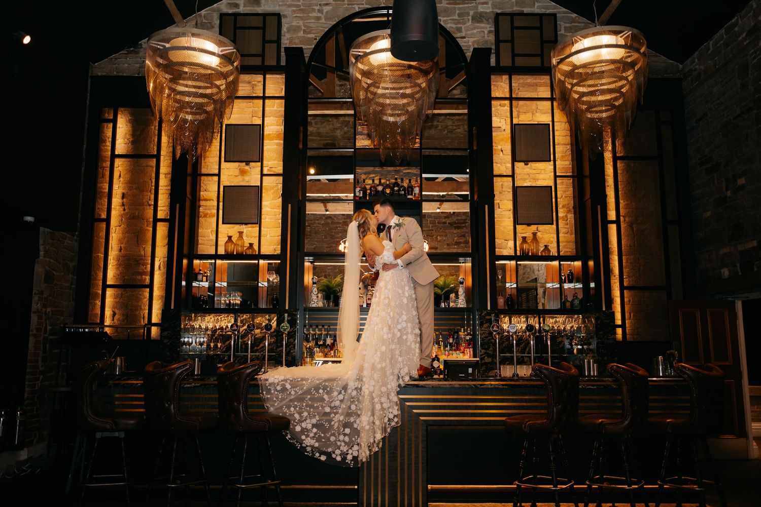 Dramatic nighttime wedding photos in front of an illuminated building with classical architecture.