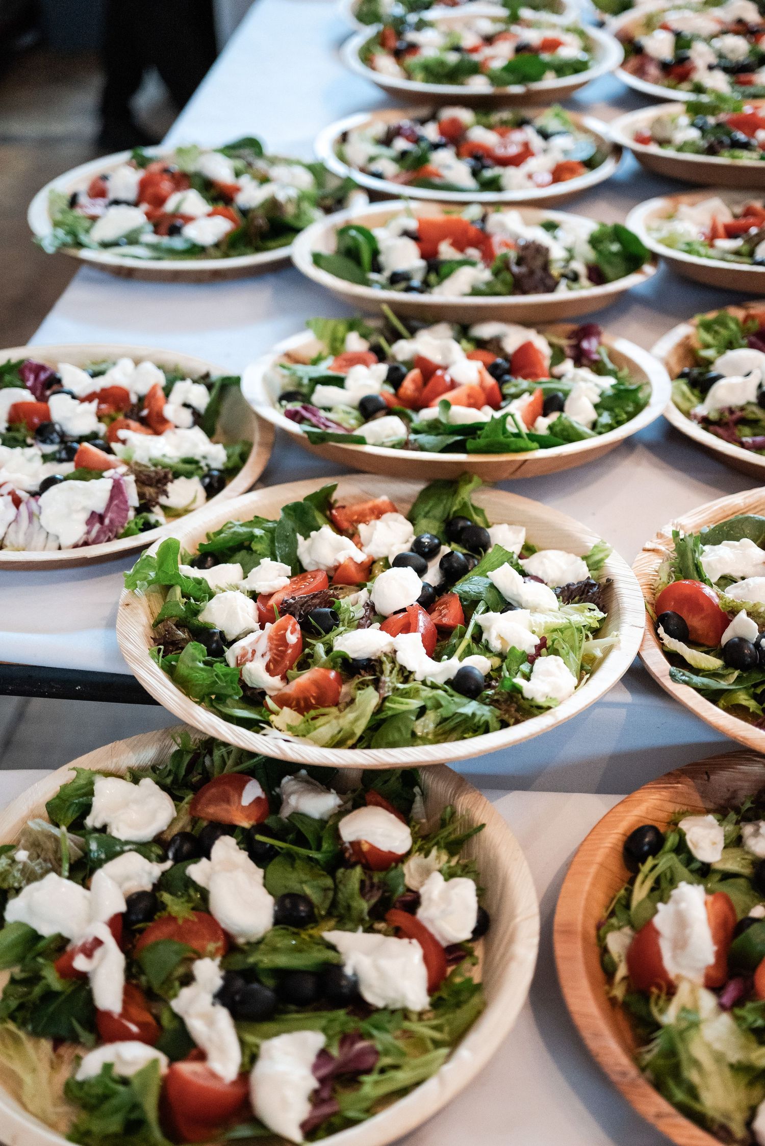 Fresh garden salads with strawberries and white dressing arranged on wooden serving boards.