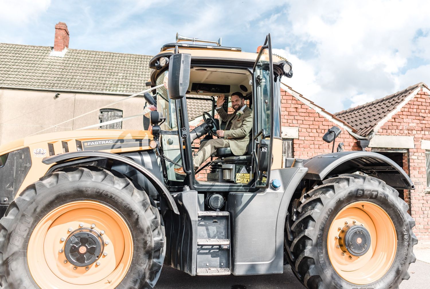 View of a modern farm tractor with someone visible in the operator's cabin.
