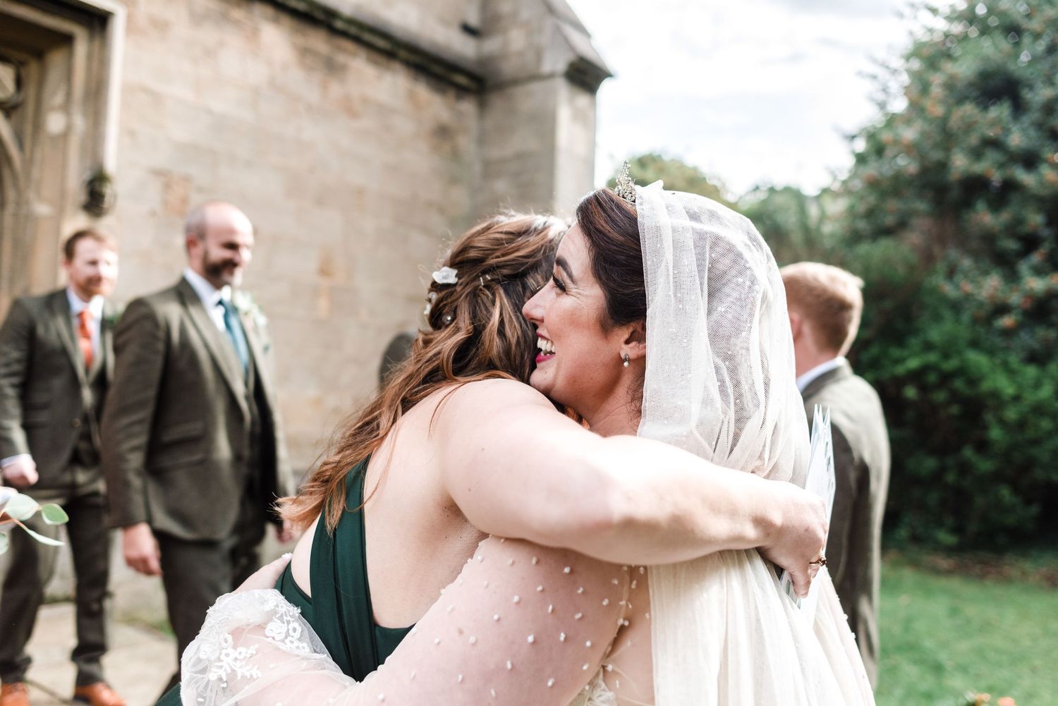 Emotional embrace outside a stone church during wedding celebrations.